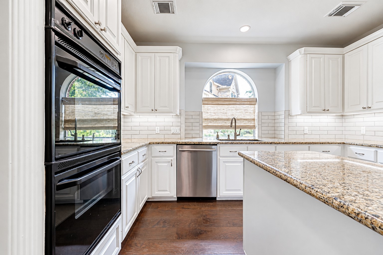 PLENTY OF ROOM TO GET CREATIVE IN THE KITCHEN! Whether preparing a quick weeknight dinner or a special holiday meal, the double ovens make it easier to manage multiple dishes at once. Generous cabinetry provides storage for cookware, dishes & everyday essentials, while the granite countertops offer plenty of room for meal preparation. The arched window above the sink brings natural light into the heart of the kitchen.
