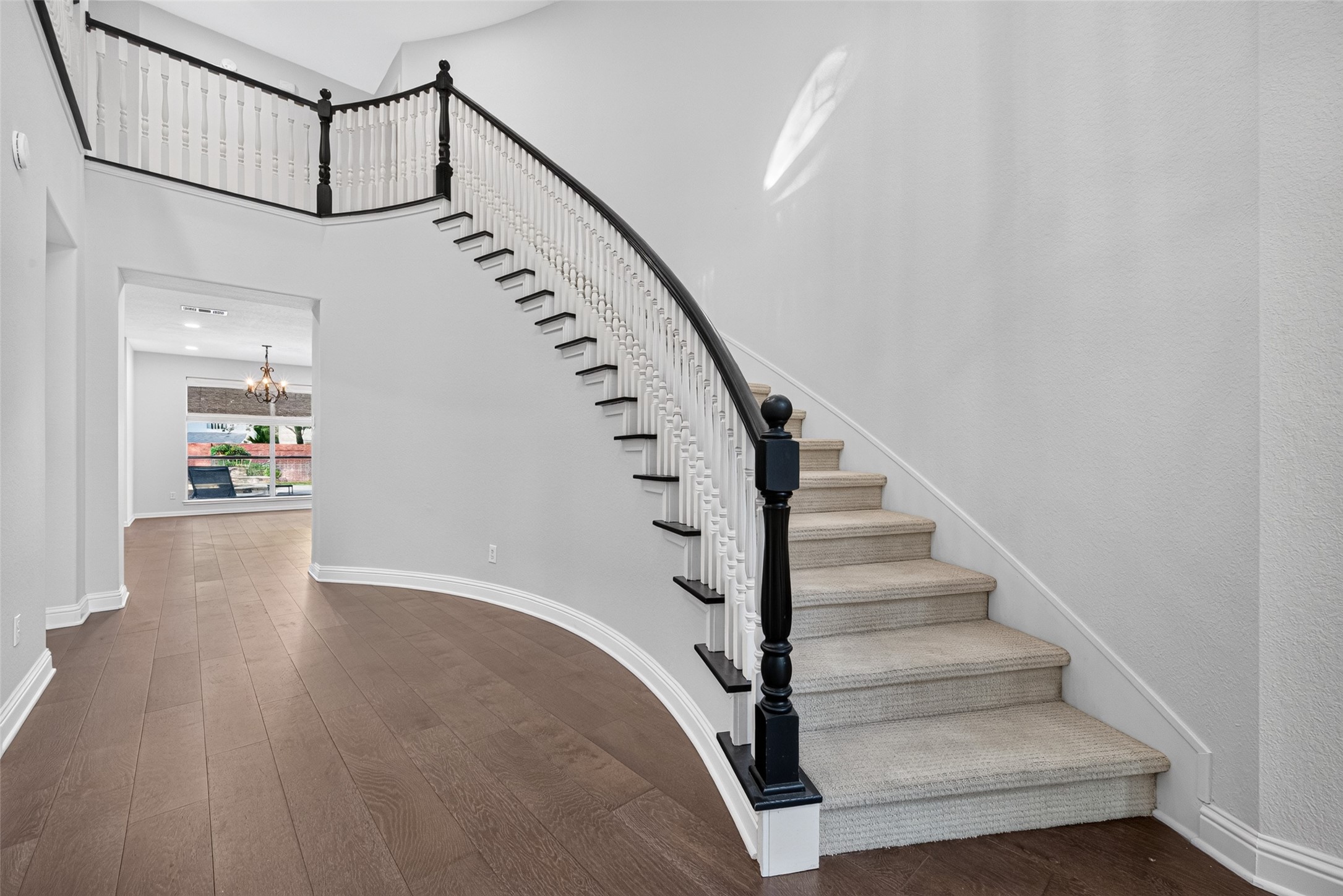 AN ELEGANT FIRST IMPRESSION! The gracefully curved staircase is a beautiful architectural centerpiece, with its contrasting dark handrail, white balusters and sweeping design. Wood flooring continues through the foyer and adjoining living spaces, creating a warm, cohesive look. It's easy to imagine this space decorated for the holidays, with garland winding along the staircase and a soaring Christmas tree illuminating the foyer.