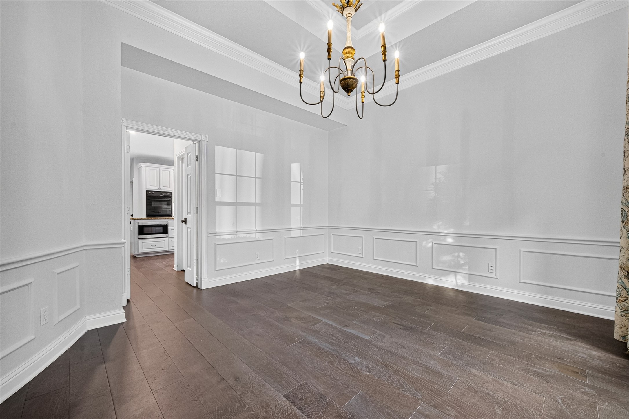 BEAUTIFUL DETAILS FROM EVERY ANGLE! This view offers another look at the Formal Dining Room's tray ceiling, elegant chandelier, decorative molding and beautiful wood flooring. Notice the doorway leading directly into the Kitchena convenient connection when bringing dinner to the table, serving guests or returning for seconds during a holiday feast. Thoughtfully positioned, these two rooms naturally complement one another.