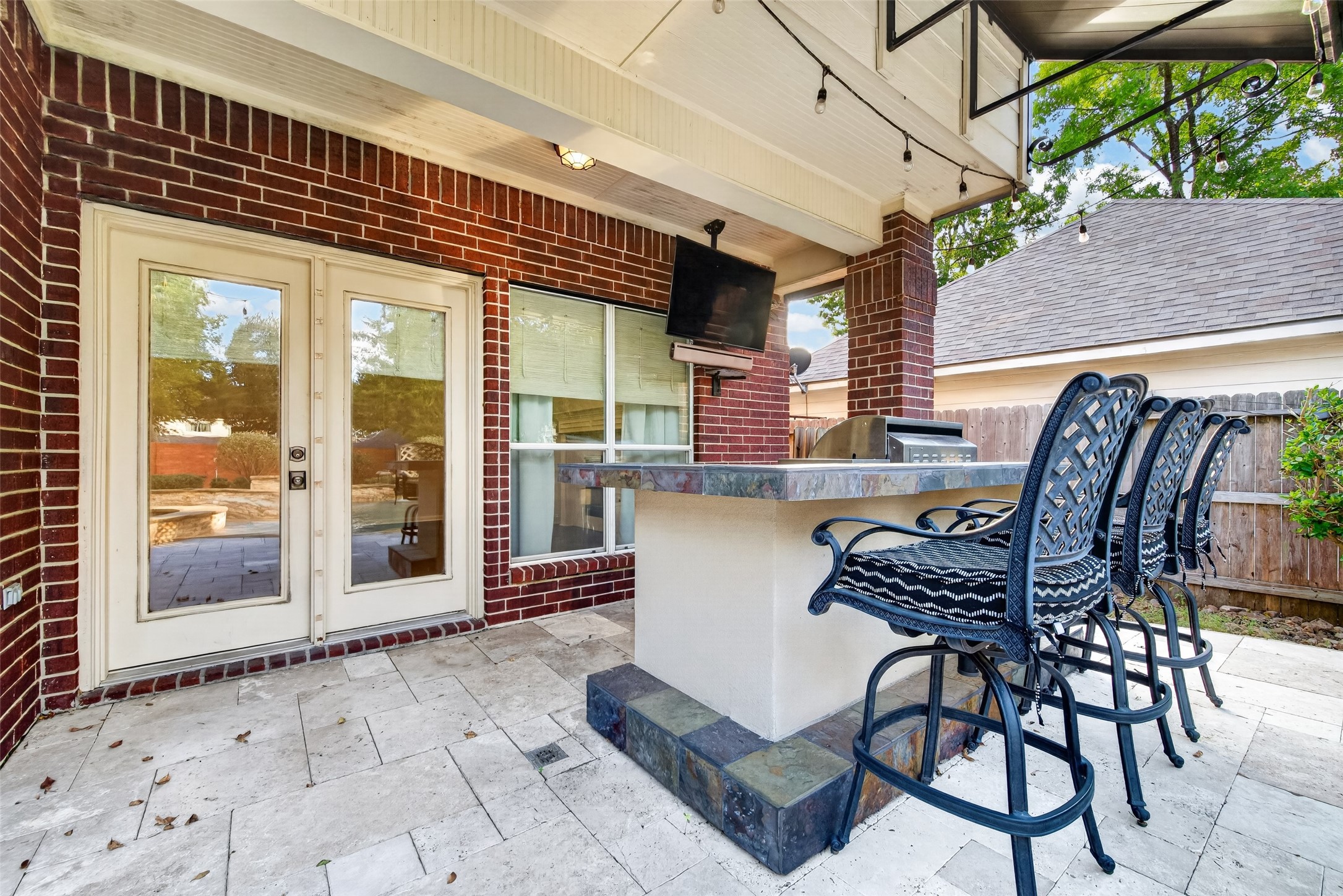 PULL UP A CHAIR & STAY AWHILE! The covered outdoor bar offers a wonderful gathering spot with countertop seating, a mounted TV & easy access to the Family Room through French doors. Imagine catching the game while dinner sizzles on the grill, sharing appetizers with friends or simply relaxing after an afternoon in the pool. With string lights overhead & the outdoor kitchen just steps away, entertaining here is easy!