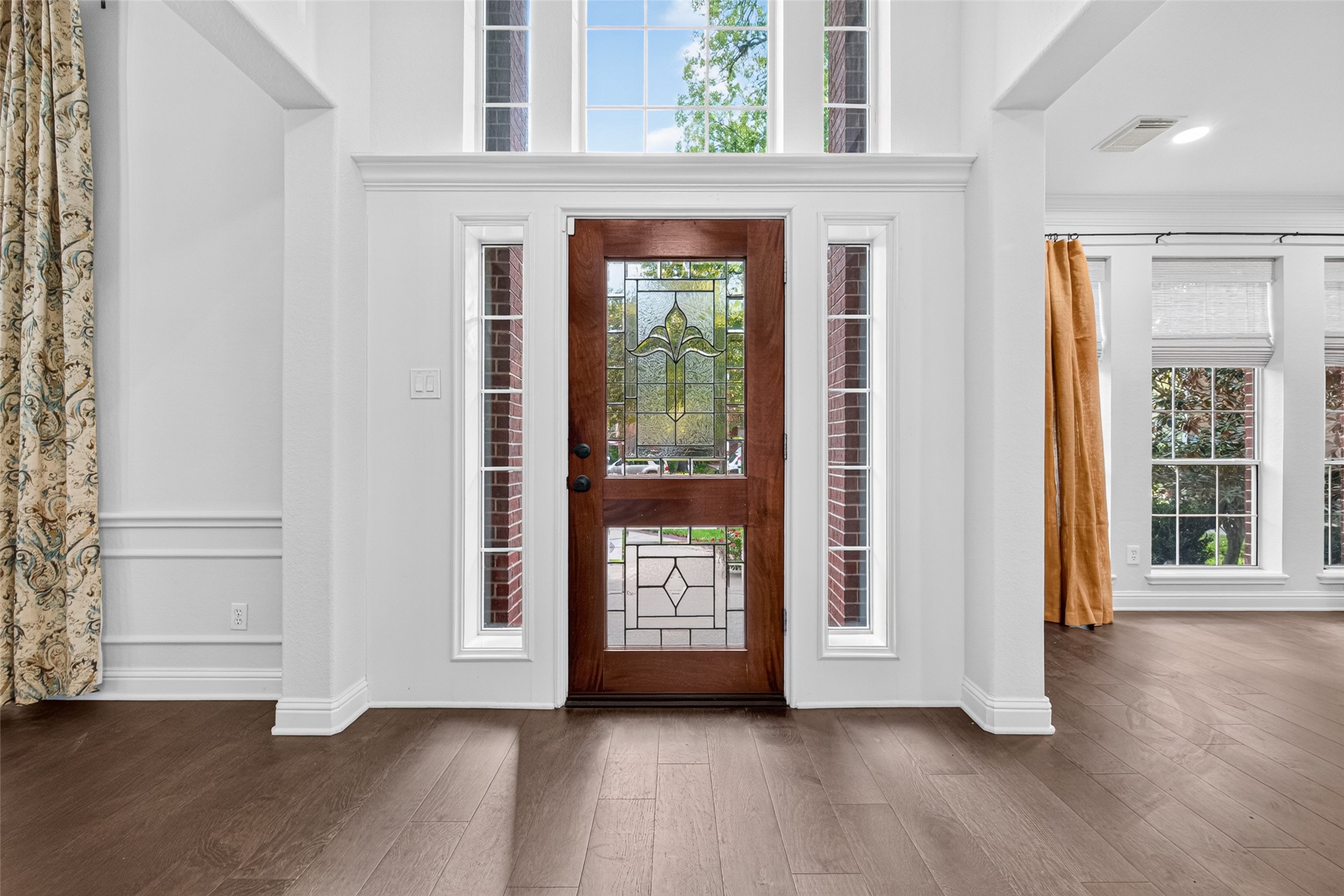 WELCOME INSIDE! Step through the beautiful leaded-glass front door into an impressive foyer with a soaring 2-story ceiling, elegant architectural details and beautiful wood flooring. The Formal Dining Room is to your left, while the Formal Living Room is to your right. Straight ahead, the sweeping staircase creates a memorable first impression and sets the tone for the spaces waiting to be discovered throughout this home.