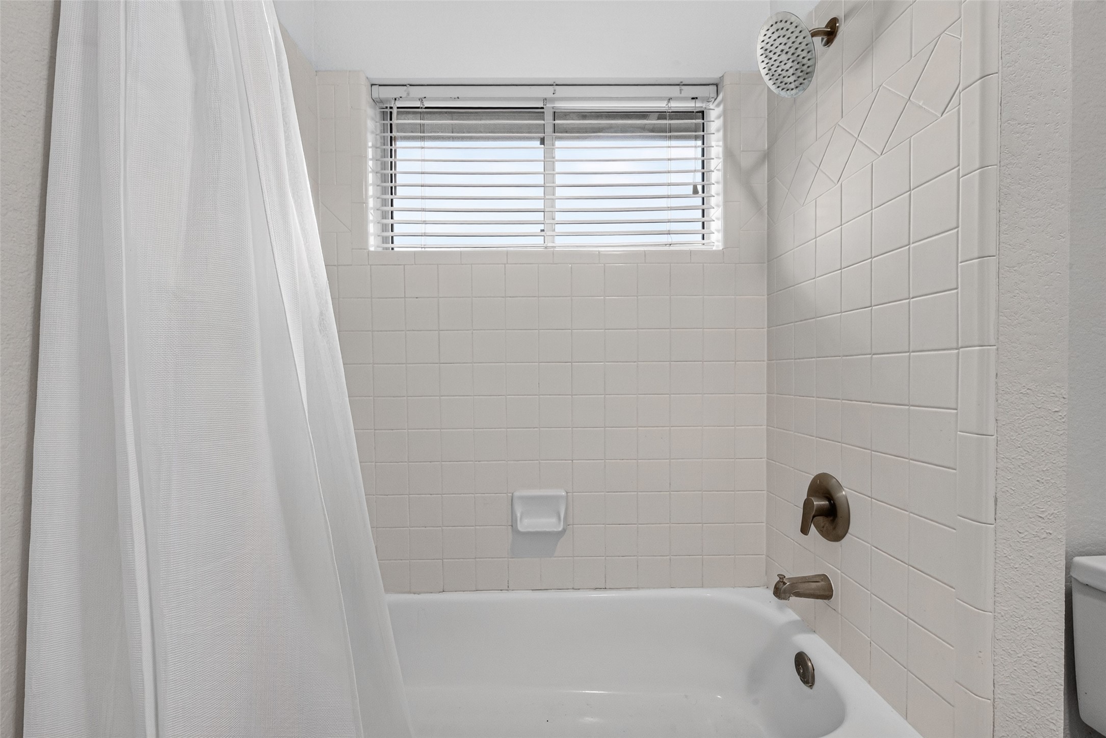 CONVENIENCE BETWEEN TWO BEDROOMS! The shared bathing area features a tub/shower combination with white tile surround, a decorative tile accent & a window welcoming natural light. A separate water closet provides additional privacy, while the connecting vanity areas make this Jack & Jill arrangement especially practical.
