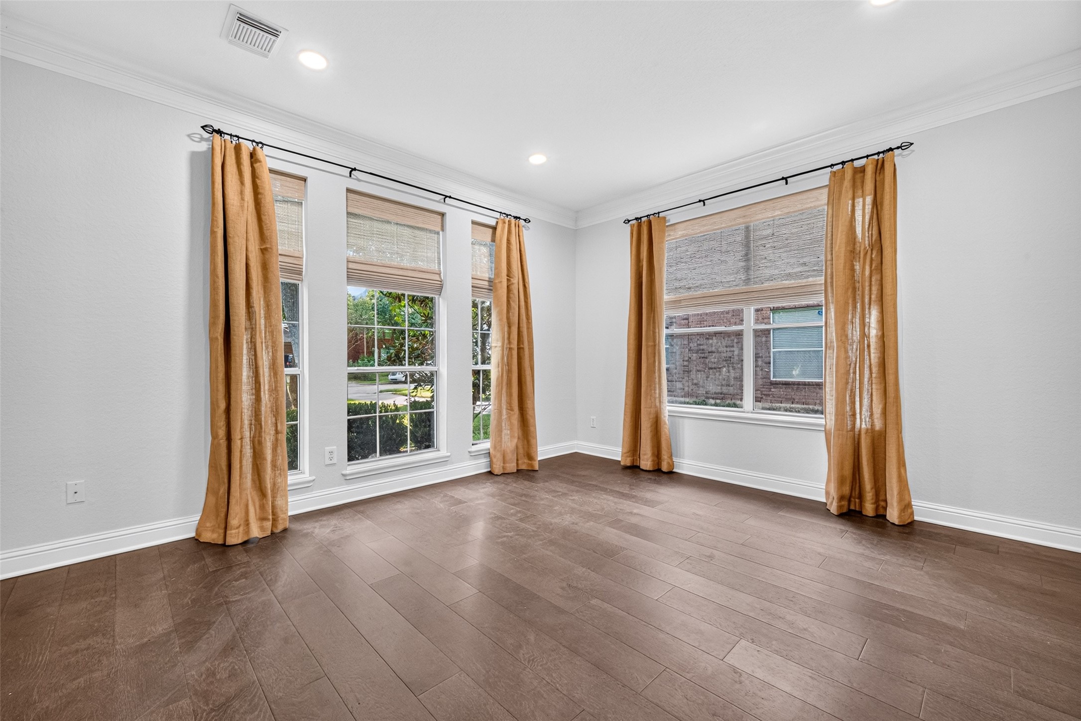 A ROOM FILLED WITH POSSIBILITIES! This Formal Living Room features beautiful wood flooring, crown molding and tall windows with woven blinds that welcome natural light. While traditionally designed as a formal sitting room, today's lifestyle might call for something different. Perhaps a comfortable conversation area, second study, music room with a piano or quiet library and reading retreat? With its generous proportions and beautiful windows, this room offers flexibility to make it your own.