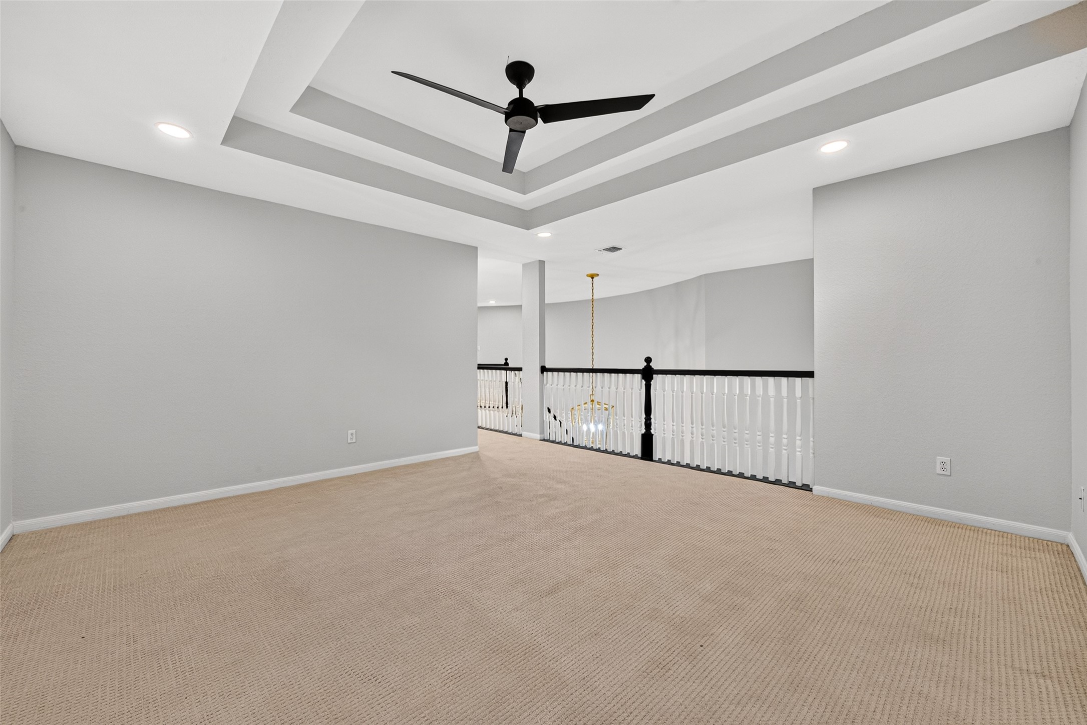 A LITTLE SEPARATION GOES A LONG WAY! This view offers another perspective of the spacious upstairs Game Room, highlighting its attractive tray ceiling & open connection to the staircase landing. Thoughtfully situated apart from all the upstairs bedrooms, this versatile living area provides a separate place for watching television, playing games, pursuing hobbies or entertaining friends without disturbing those enjoying a little peace & quiet in their bedrooms.