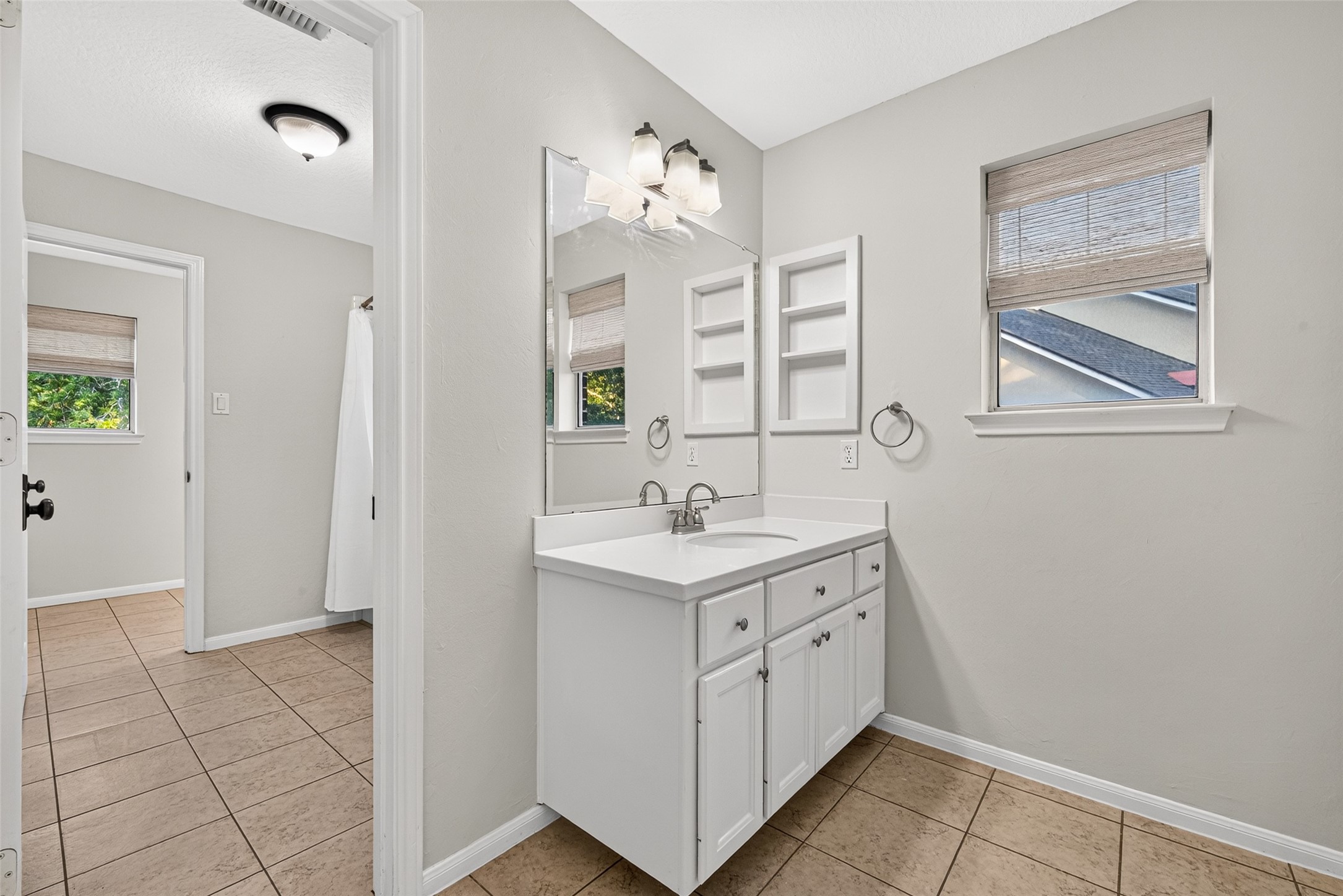 CONVENIENT ACCESS FROM THE UPSTAIRS HALLWAY! This second vanity area of Bath #2 is accessible from the hallway, making it convenient for guests enjoying the upstairs Gameroom as well as Bedroom #3. Featuring a separate sink, countertop, cabinetry, built-in shelving & a window with woven blinds, this thoughtful arrangement provides additional privacy & flexibility.