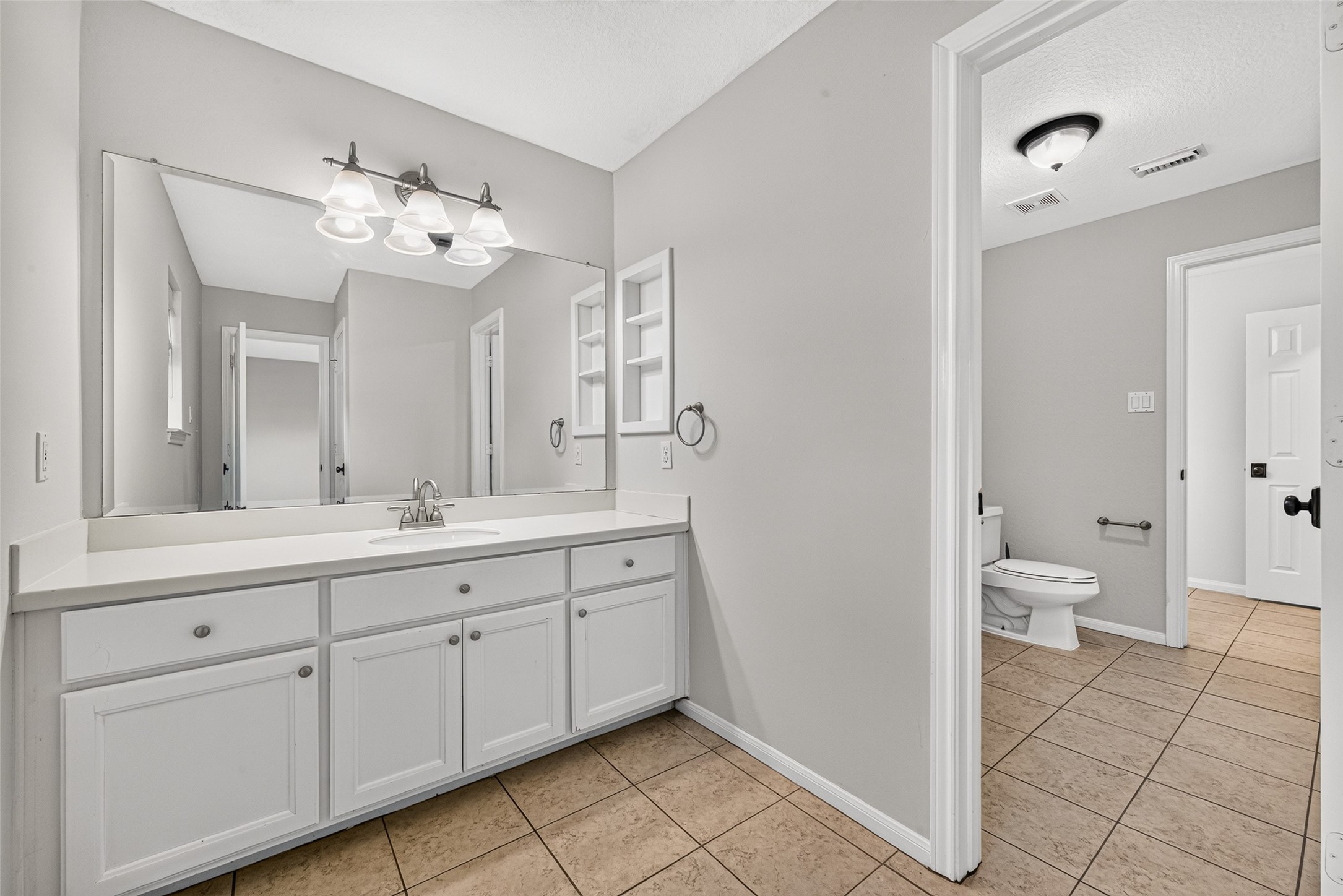 A PRACTICAL JACK & JILL BATH! Connecting Bedrooms #2 & #3, Bath #2 features separate vanity areas, allowing each bedroom convenient access to its own sink, countertop & cabinetry. This first vanity offers generous storage, a large mirror & built-in shelving for keeping everyday essentials organized.