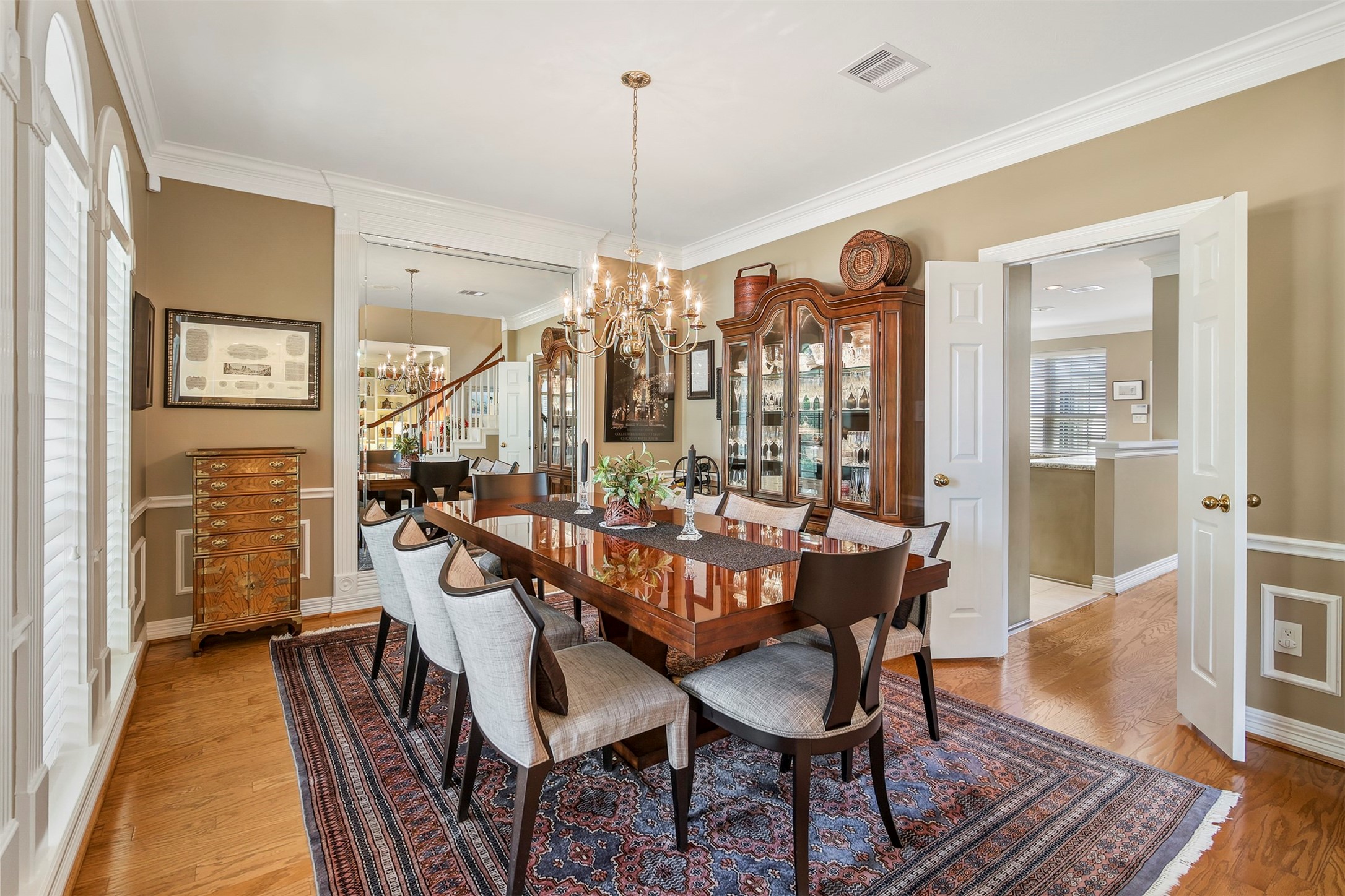 Another view of the dining room with double doors leading to the kitchen and floor to ceiling mirror.