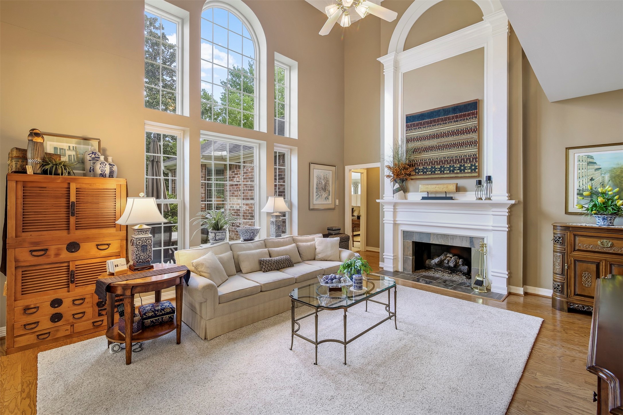 Two story family room with wood floors and gas log fireplace. The fireplace has stone surround and mantle with two story trim detail.