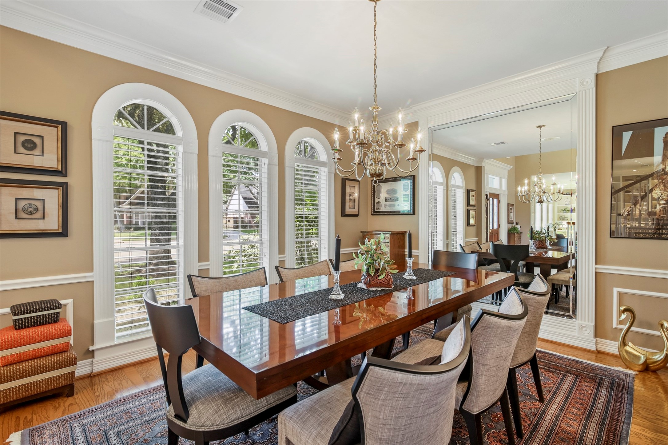 Spacious dining room features wood floors, decorative trim work throughout to include wainscotting, crown molding and arched floor to ceiling windows.
