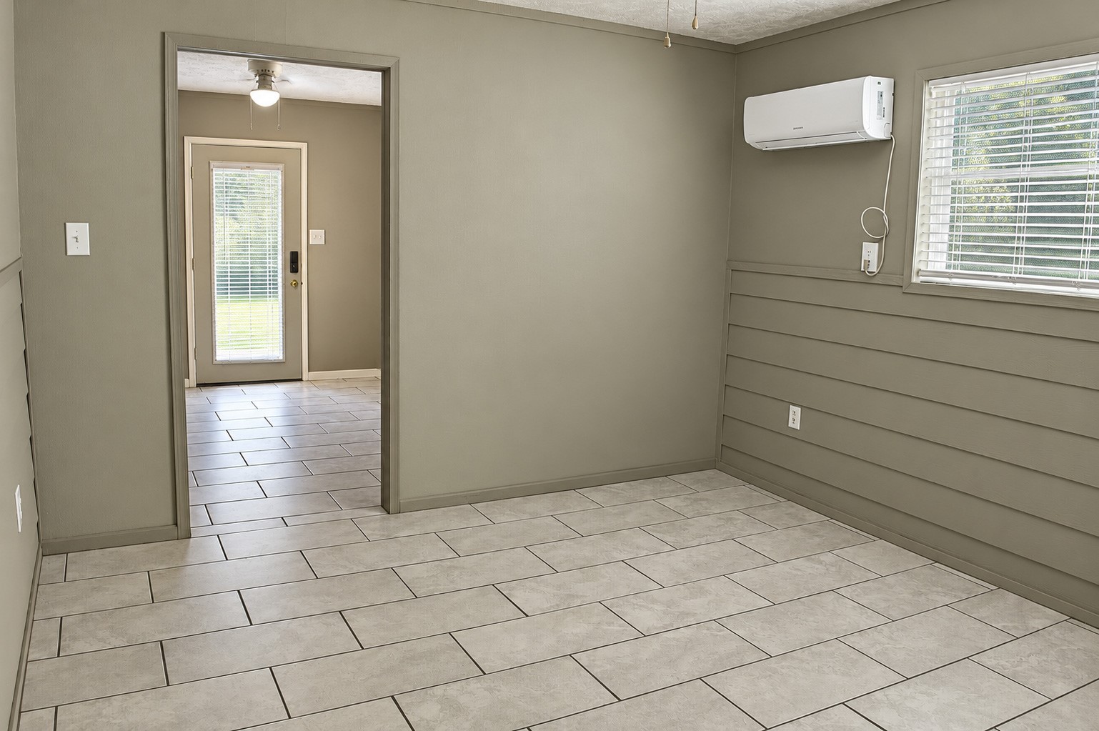 Bright, airy multiuse room in the barn with neutral tile flooring, a window for natural light, and a mini-split AC for comfort.