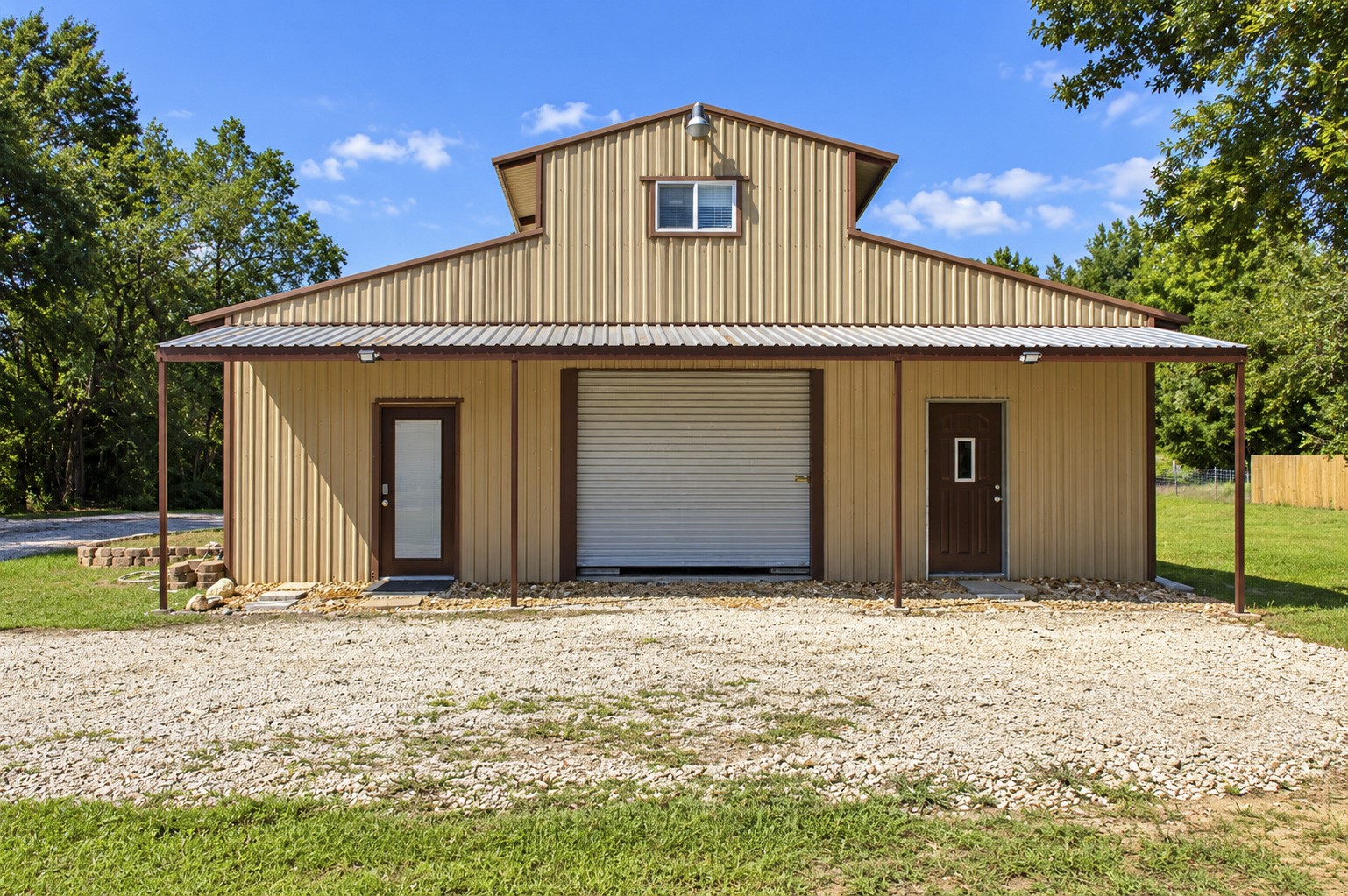Spacious metal barn building with a large central garage door and two side entry doors to multipurpose quarters, and a 3 quarter on the 2nd floor. Ideal for storage or workshop use.