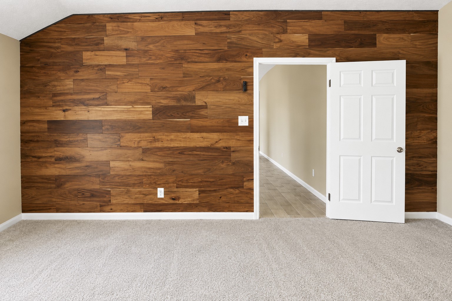 A cozy primary bedroom features a stunning wood accent wall and an inviting open doorway leading to the livingroom.