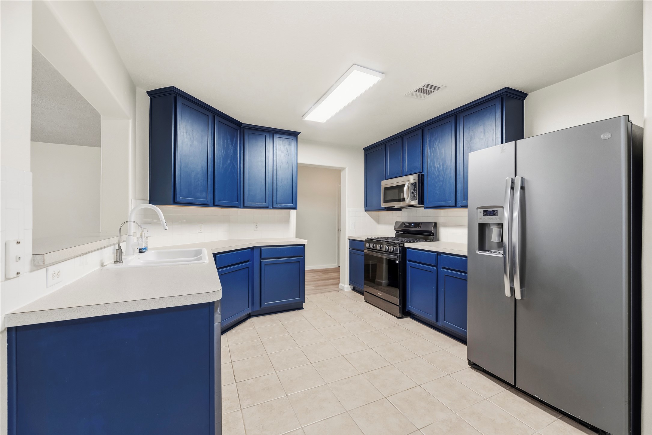 Well-appointed kitchen featrures painted cabinets, tile backsplash, stainless steel appliances, gas range and a breakfast bar.