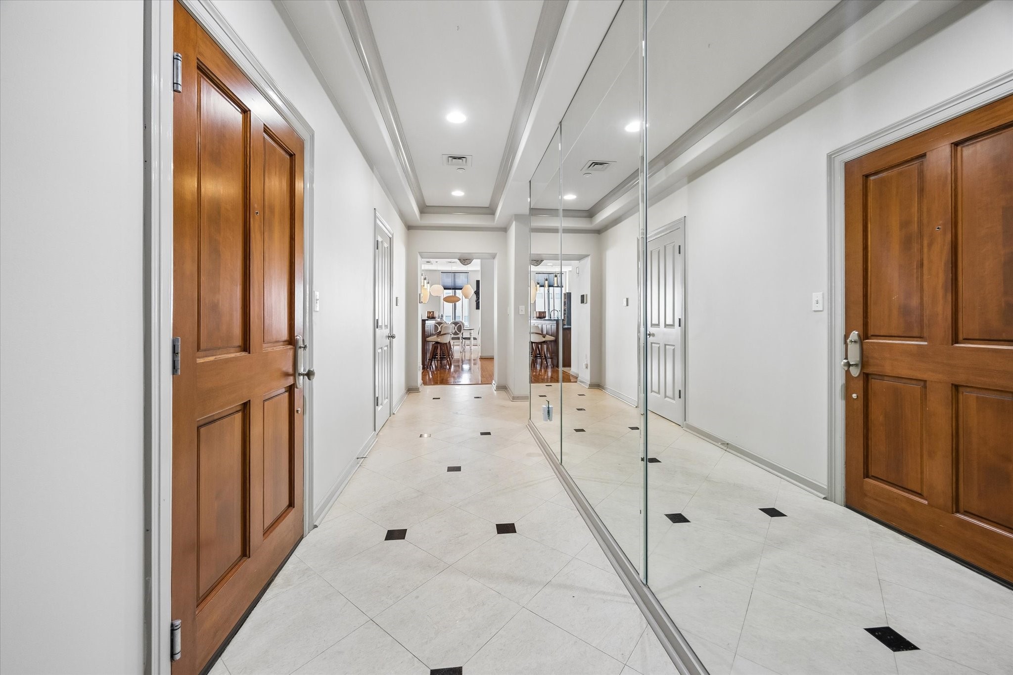 A grand entryway welcomes you with elegant tile flooring, mirrored walls, and rich wooden doors, leading seamlessly into the heart of the home.