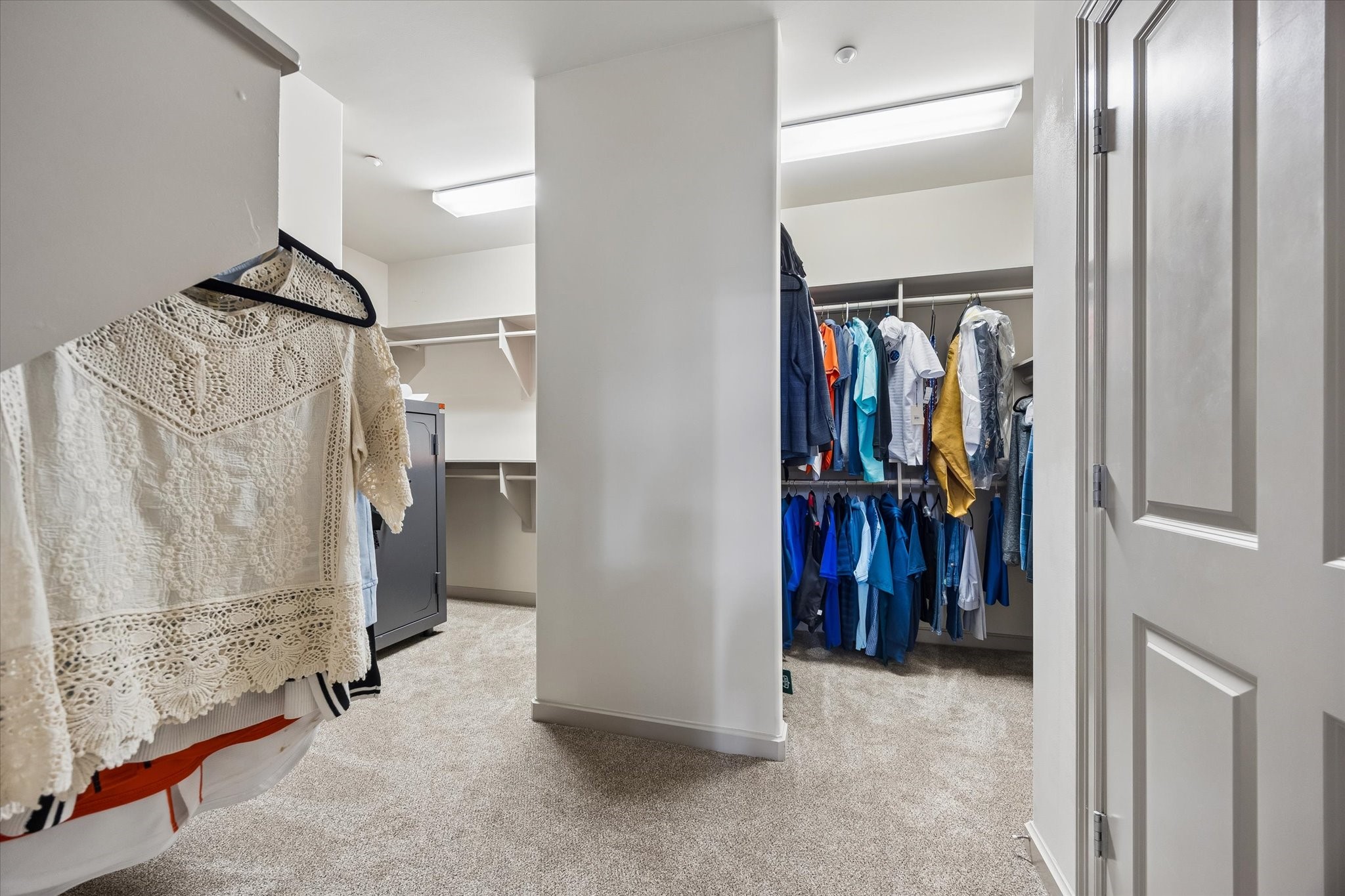Spacious walk-in primary closet featuring ample hanging space and shelving, perfect for organized storage.