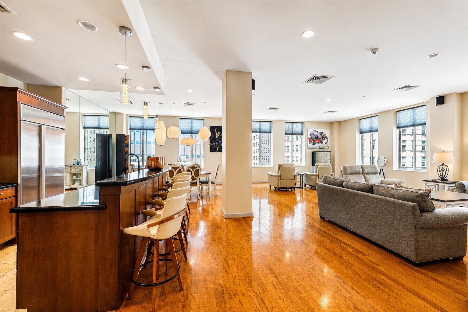 Spacious open-concept living, dining, and kitchen area featuring beautiful hardwood floors, abundant natural light, large windows, and a generous kitchen island with bar seating. An inviting layout with plenty of room for entertaining and everyday living.