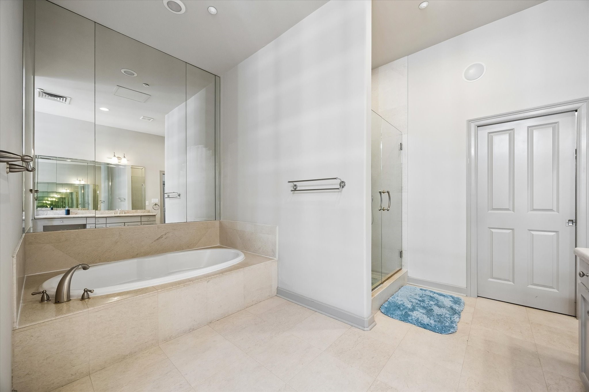 Elegant bathroom featuring a luxurious soaking tub, glass-enclosed shower, and sleek vanity with ample mirror space.