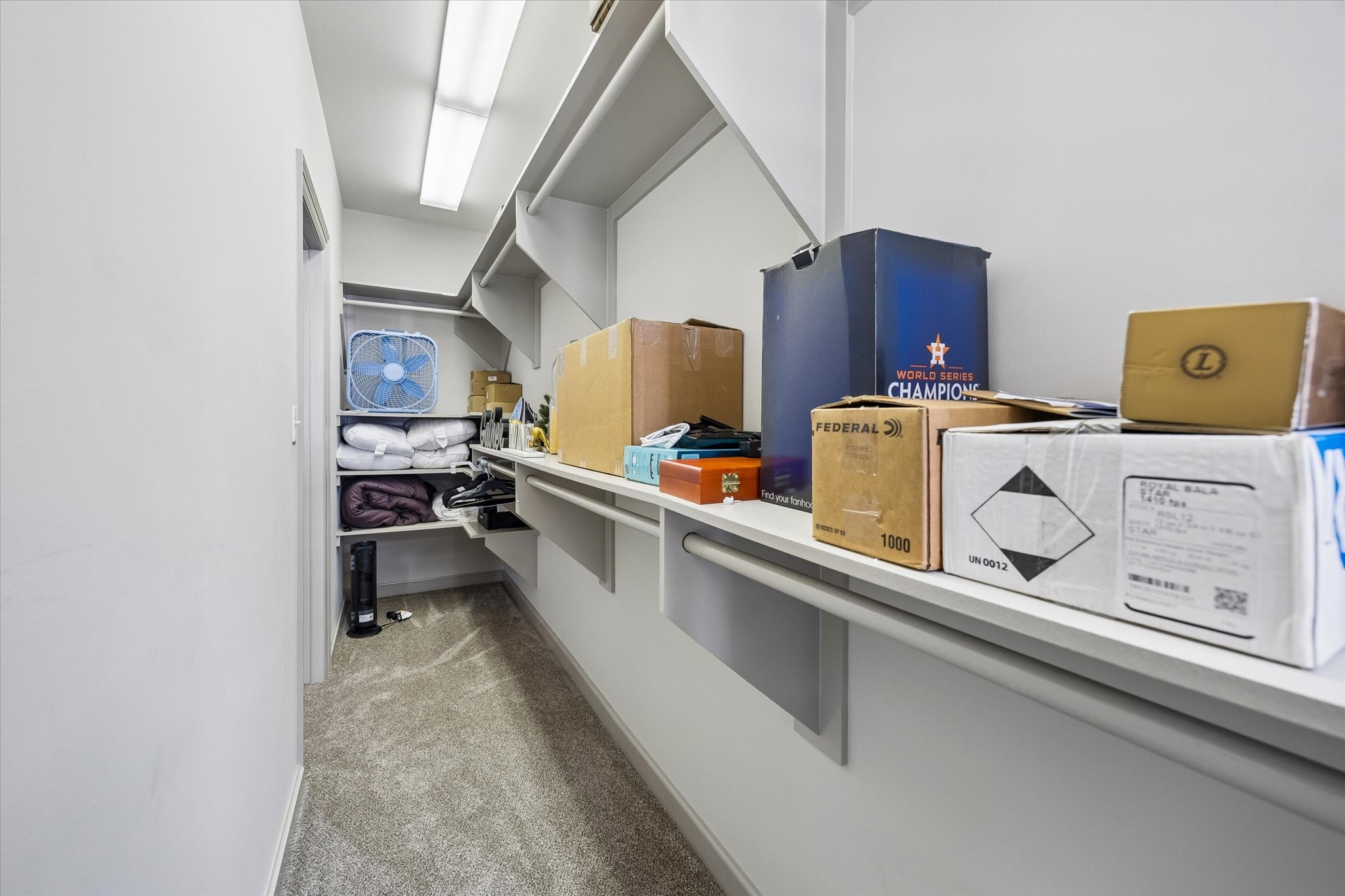 Spacious bedroom walk-in closet with built-in shelves, perfect for organizing boxes and household items.