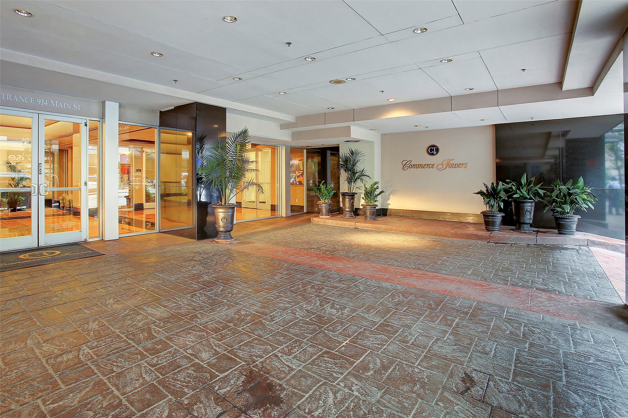 Elegant entrance to Commerce Towers, featuring a covered walkway, potted plants, and well-lit glass doors for a sophisticated welcome.