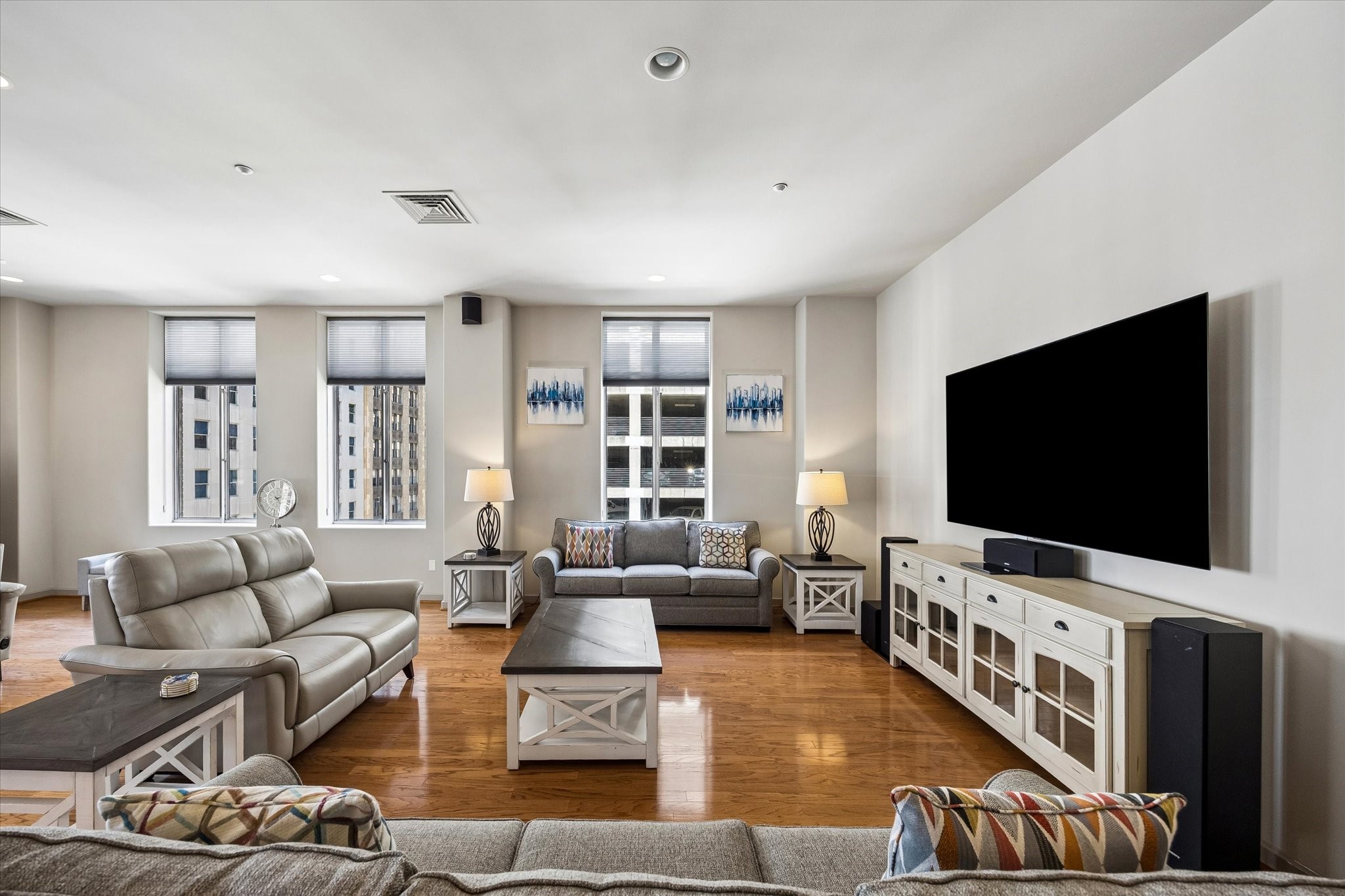 Spacious living room with elegant hardwood floors and ample natural light, featuring cozy seating arrangements, modern furnishings, and a sleek mounted TV for entertainment. Spacious living room with elegant hardwood floors and ample natural light, featuring cozy seating arrangements, modern furnishings, and a sleek mounted TV for entertainment.