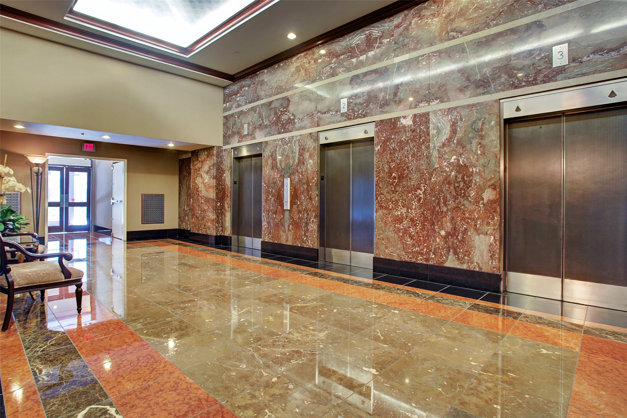 Elegant lobby featuring polished marble floors and walls, complemented by a row of modern elevators, offering a luxurious entrance experience.