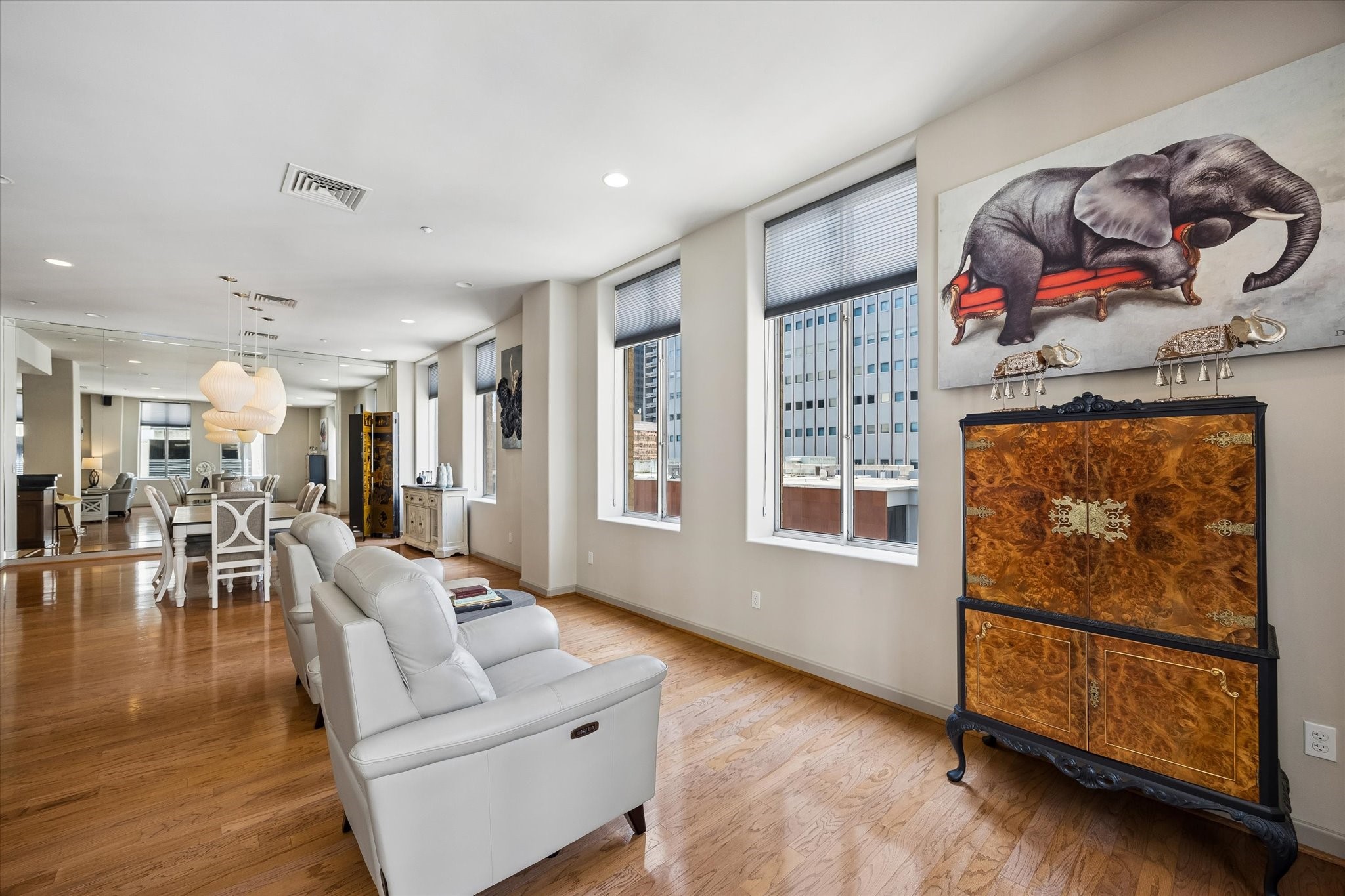 Spacious, modern living area with sleek hardwood floors, abundant natural light from large windows, and elegant white seating. Spacious, modern living area with sleek hardwood floors, abundant natural light from large windows, and elegant white seating.