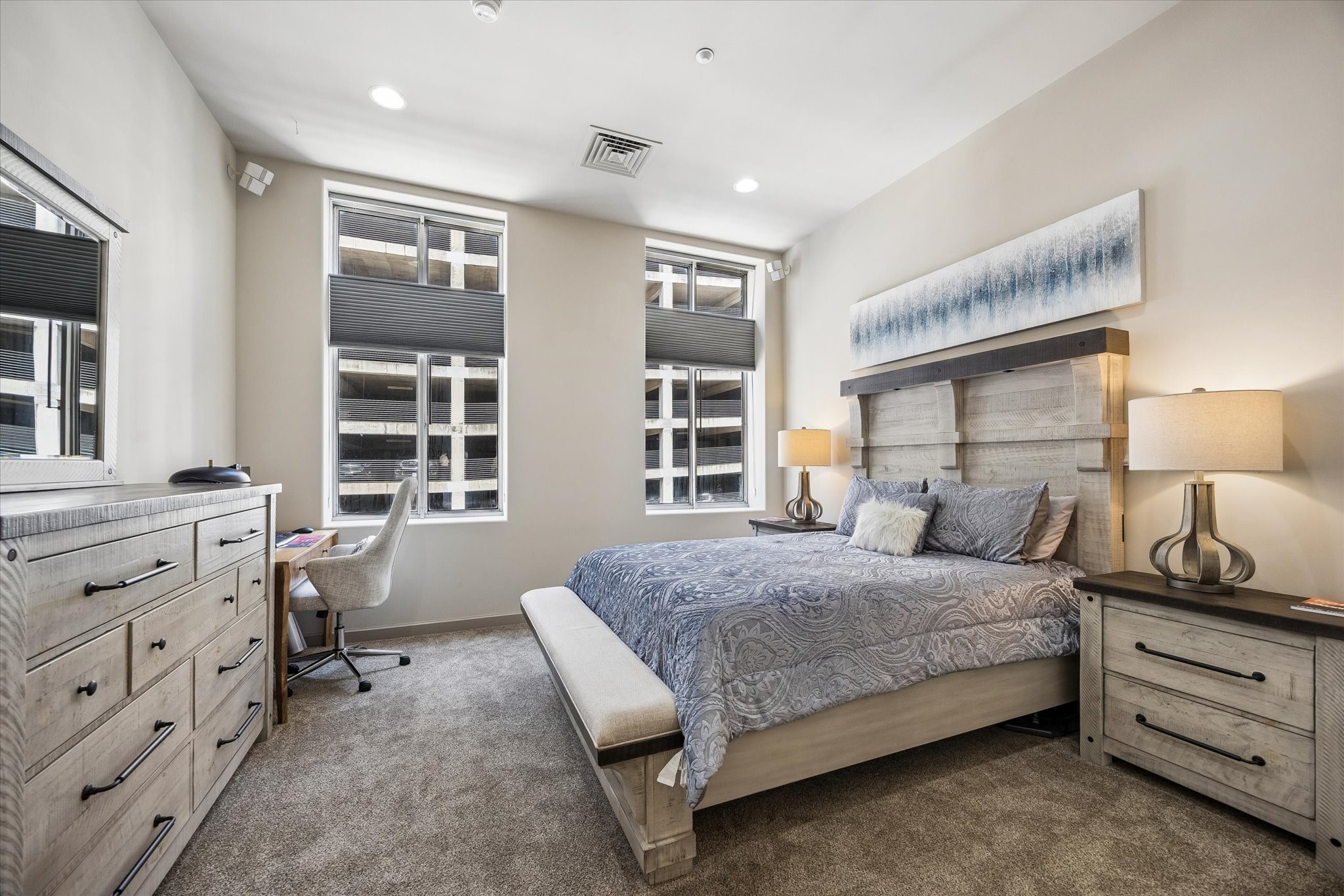 Spacious bedroom with large windows, stylish furnishings, and ample natural light, creating a cozy and inviting atmosphere.