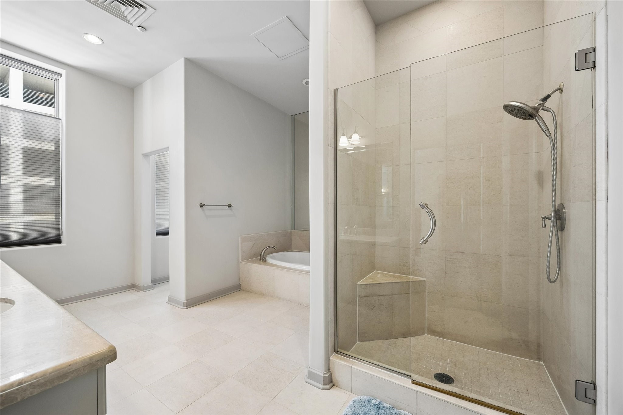 Spacious primary bathroom featuring a sleek glass-enclosed shower, elegant tile flooring, and a luxurious soaking tub for ultimate relaxation.