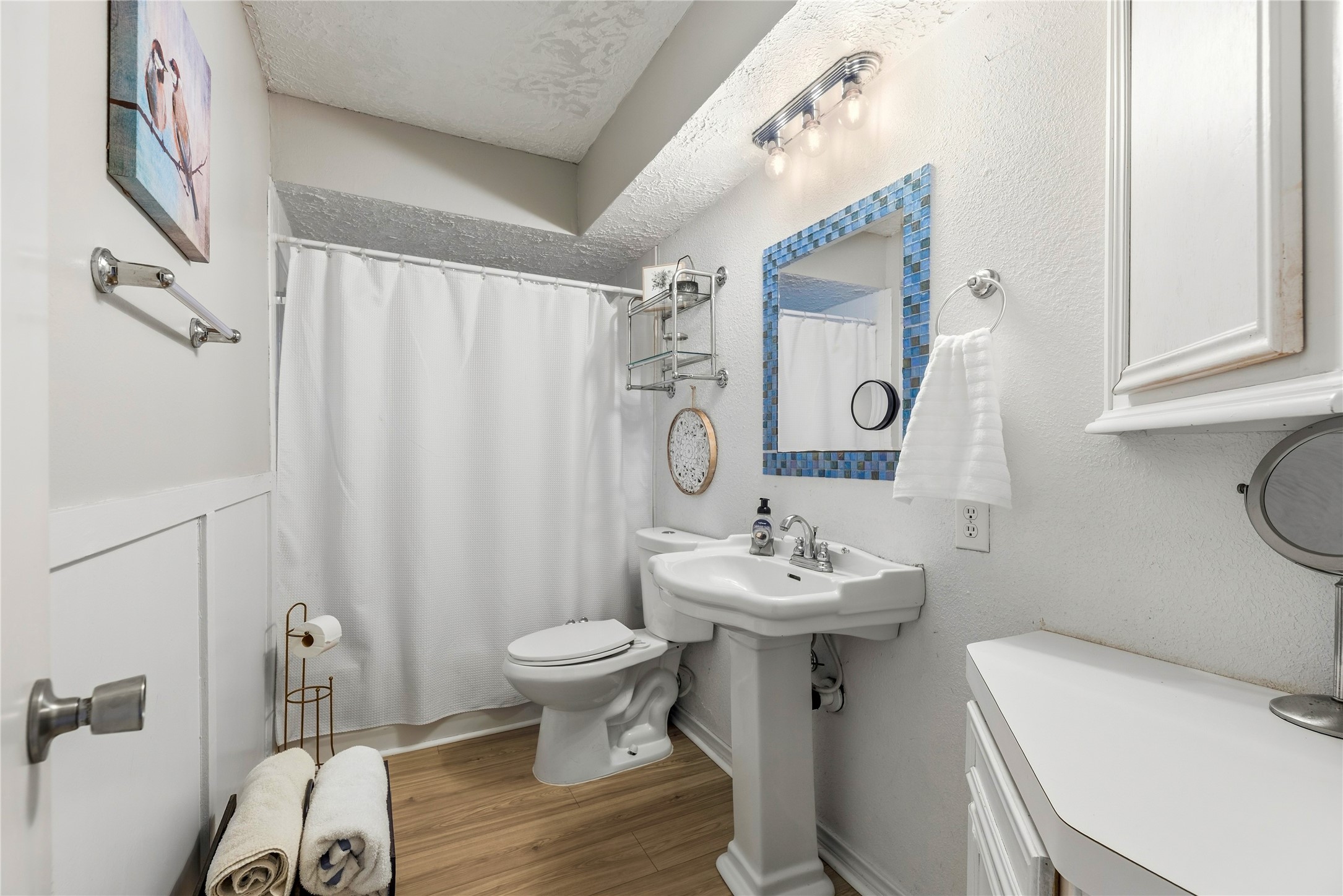 Hall bathroom with a pedestal sink, tub and shower combination, and wall storage.