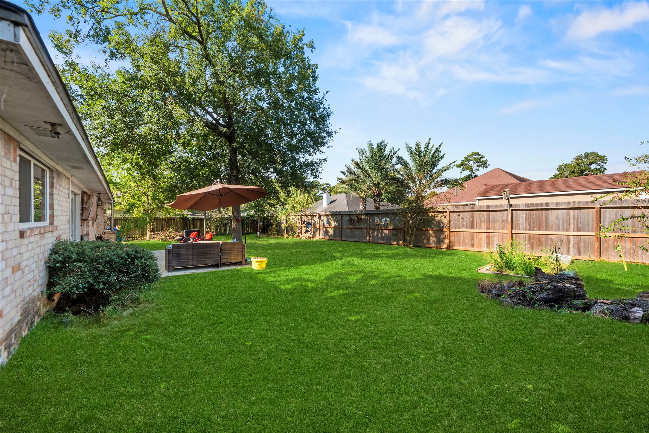Original side view of the backyard, including the existing garden bed, lawn, trees, and fence before virtual clearing.