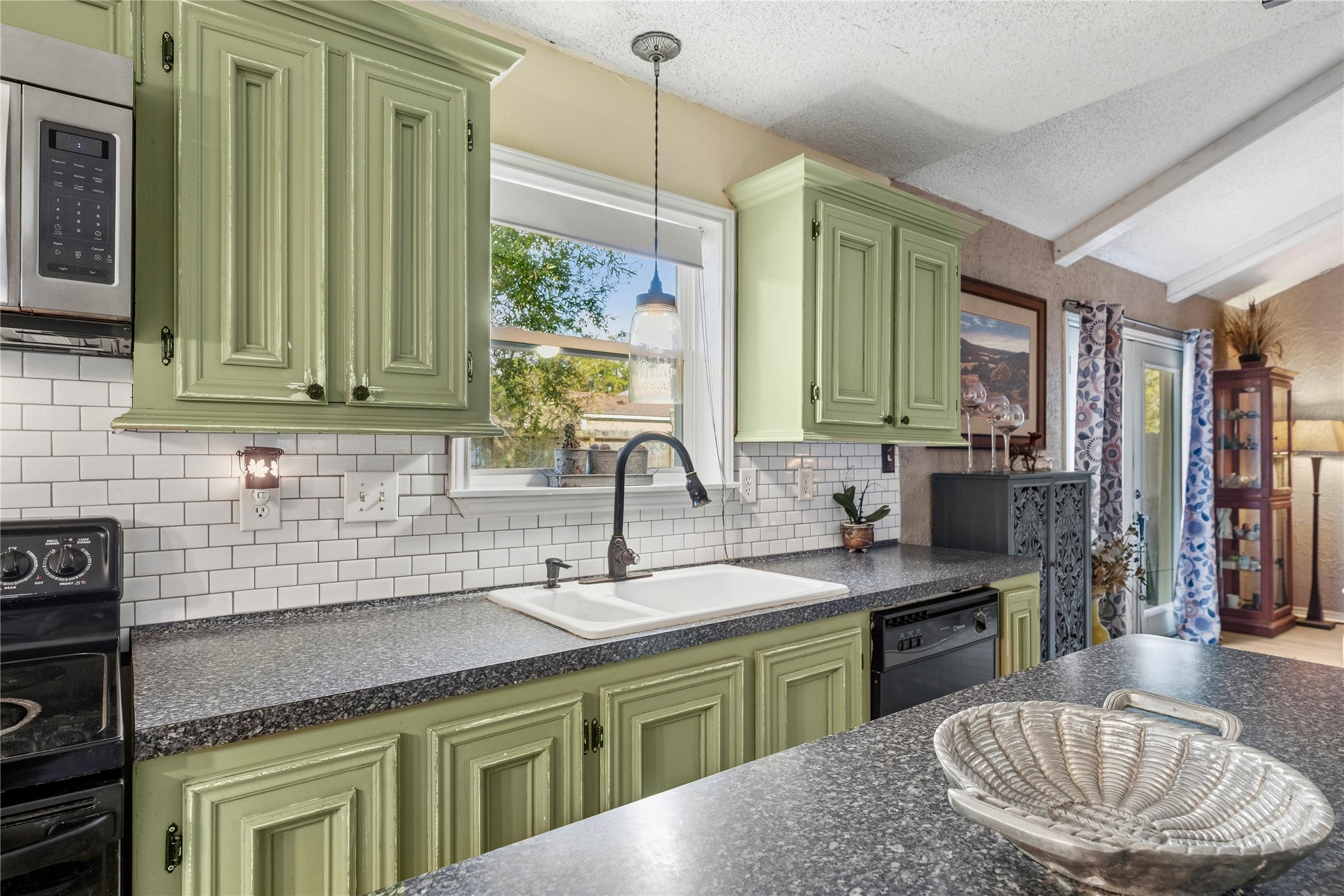 A window above the kitchen sink brings in natural light, with cabinets and counter space nearby.