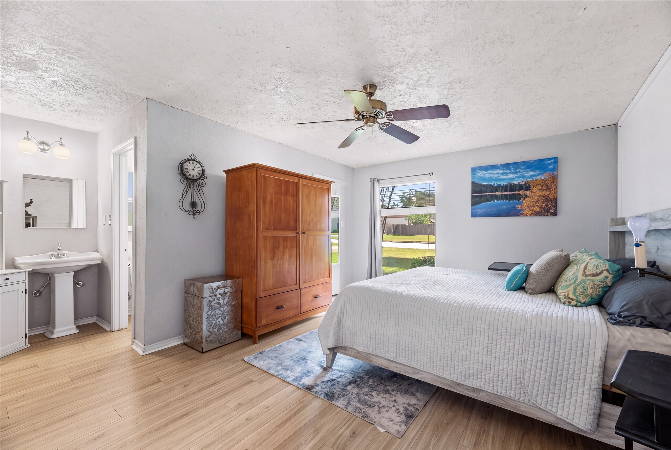 Primary bedroom with natural light, a ceiling fan, and wood-look flooring.