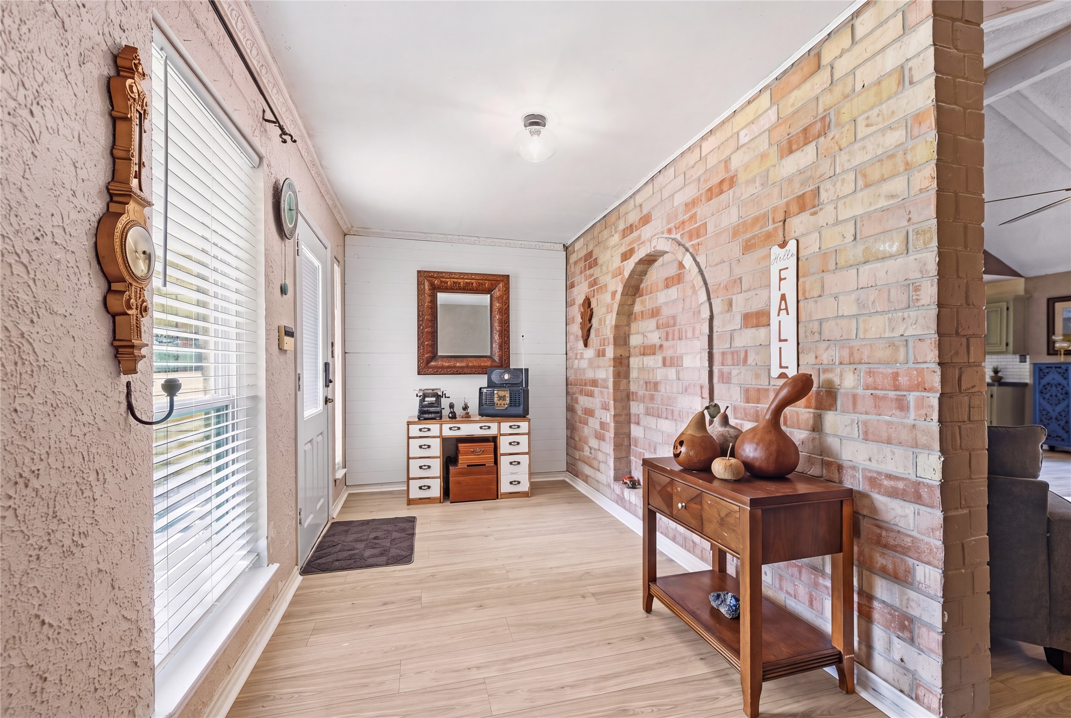 Entry corridor with a brick accent wall and a view toward the main living area.