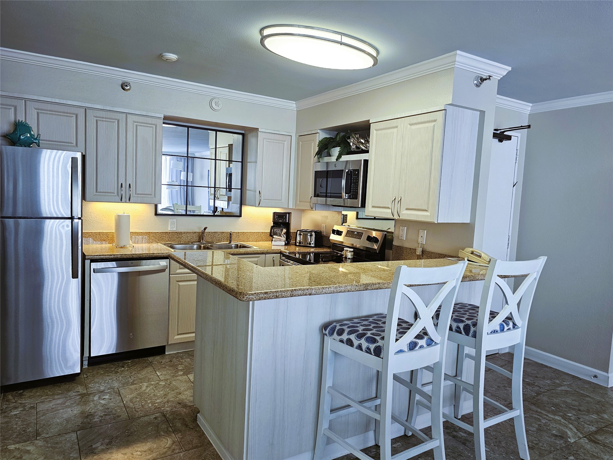 Modern kitchen with stainless steel appliances, granite countertops, and a cozy breakfast bar with stylish seating.