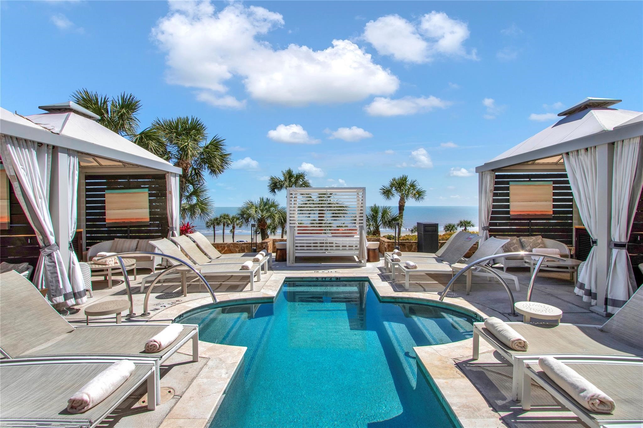 Luxurious poolside oasis with elegant cabanas and stunning ocean views, perfect for relaxation and entertaining.