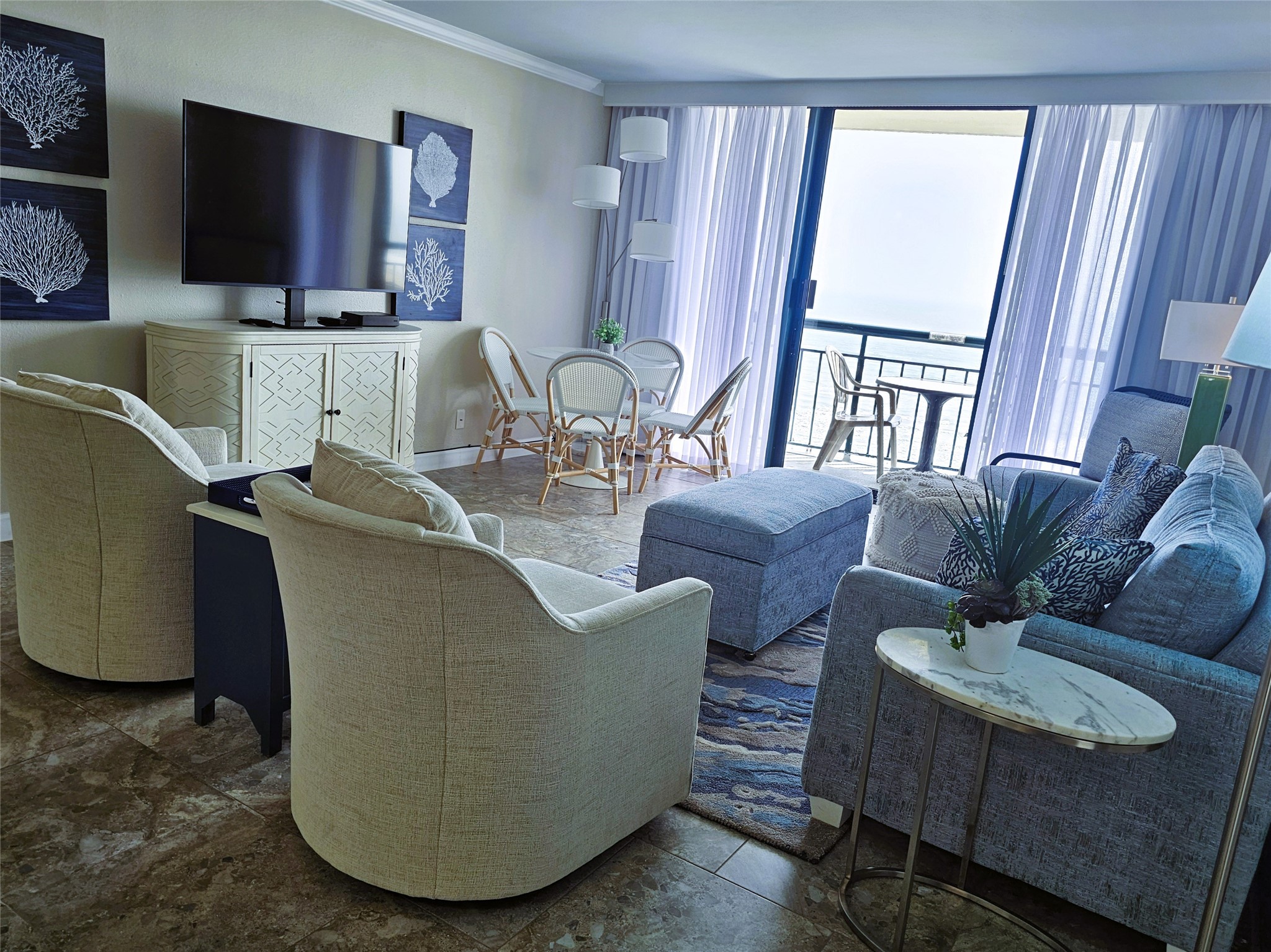 Spacious living area with modern furnishings, large TV, and sliding glass doors opening to a balcony with stunning views.