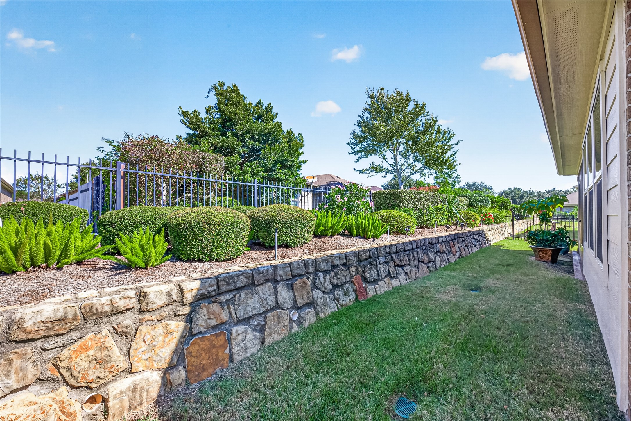A stone retaining wall adds character to the landscaped backyard.