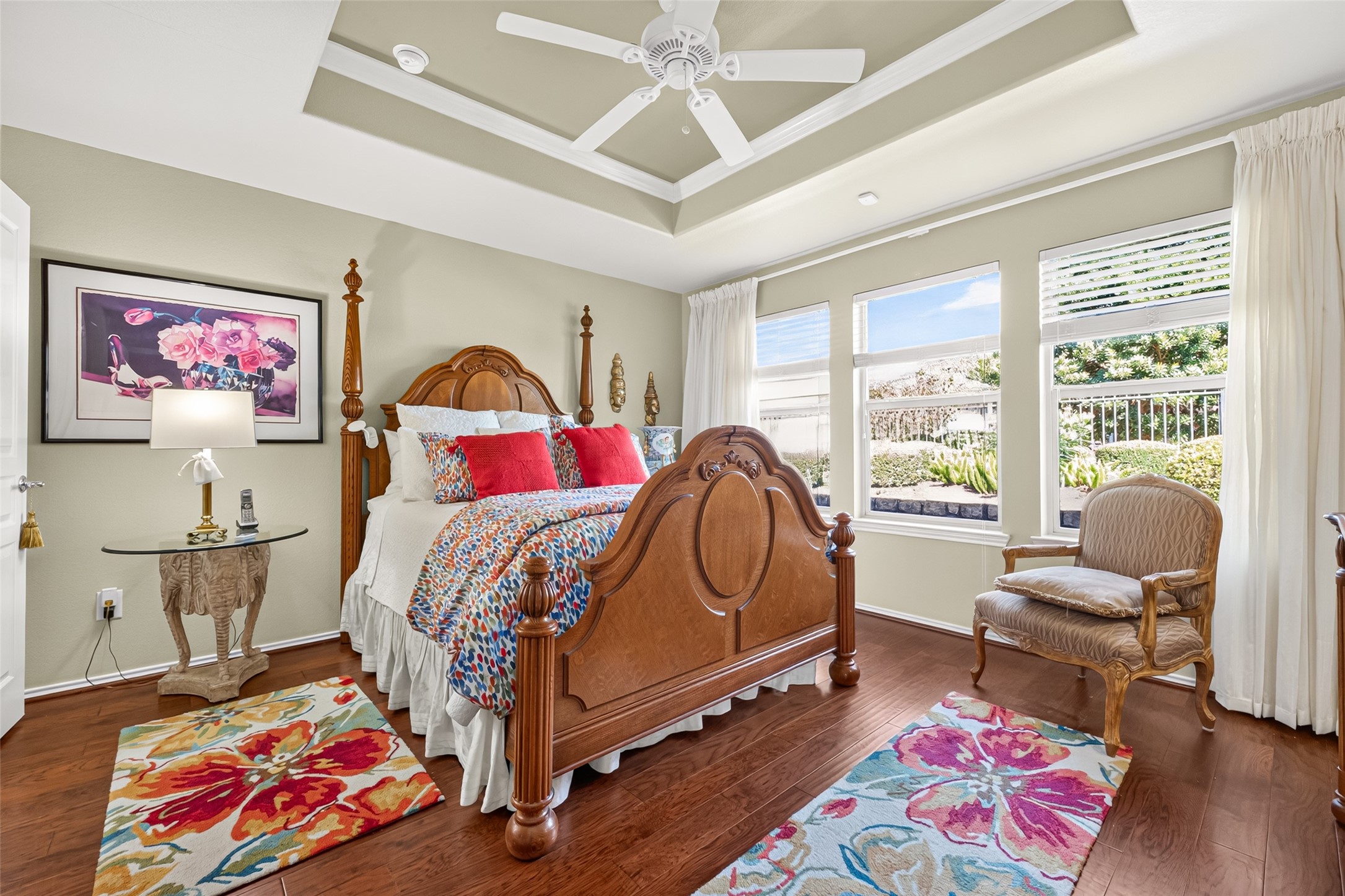 A restful primary bedroom with hardwood floors and a distinctive tray ceiling.