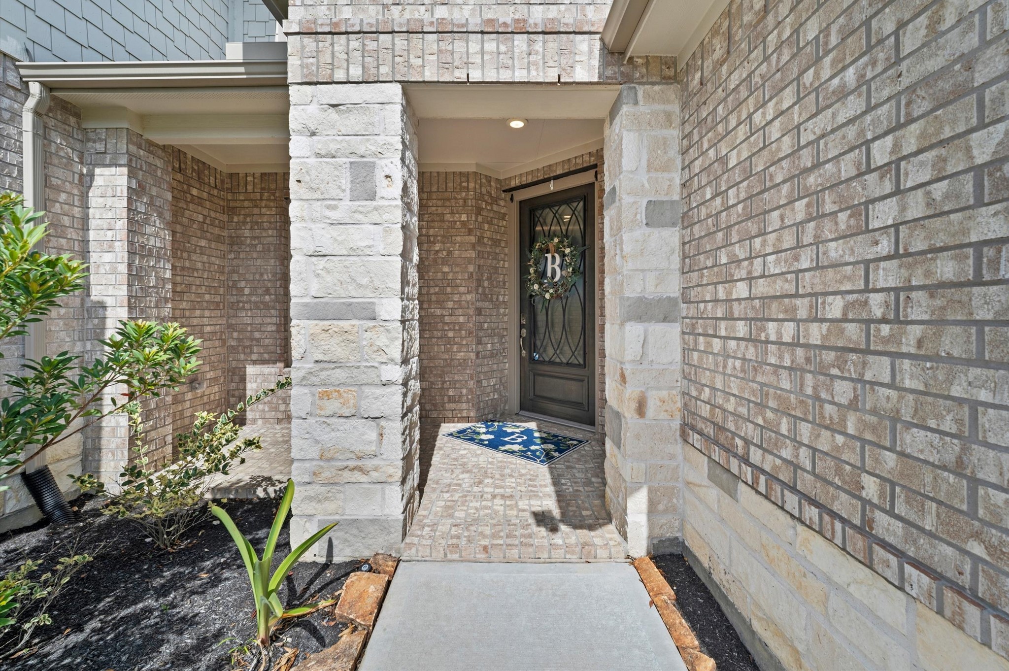 Beautiful brick entryway with elegant glass-paneled front door, and a front porch.
