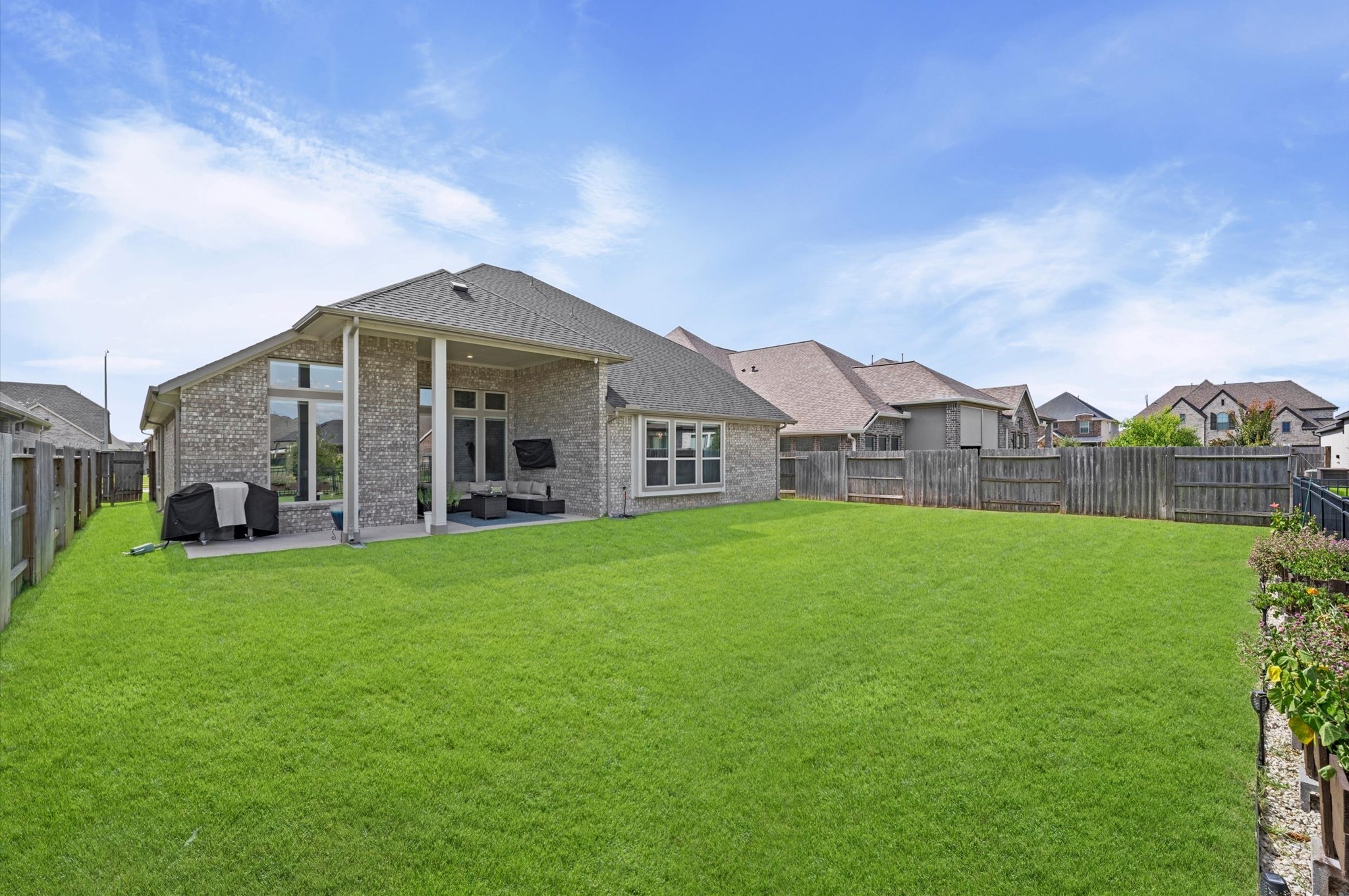 Spacious backyard with a beautifully maintained lawn, featuring a modern covered patio, and irrigation system.