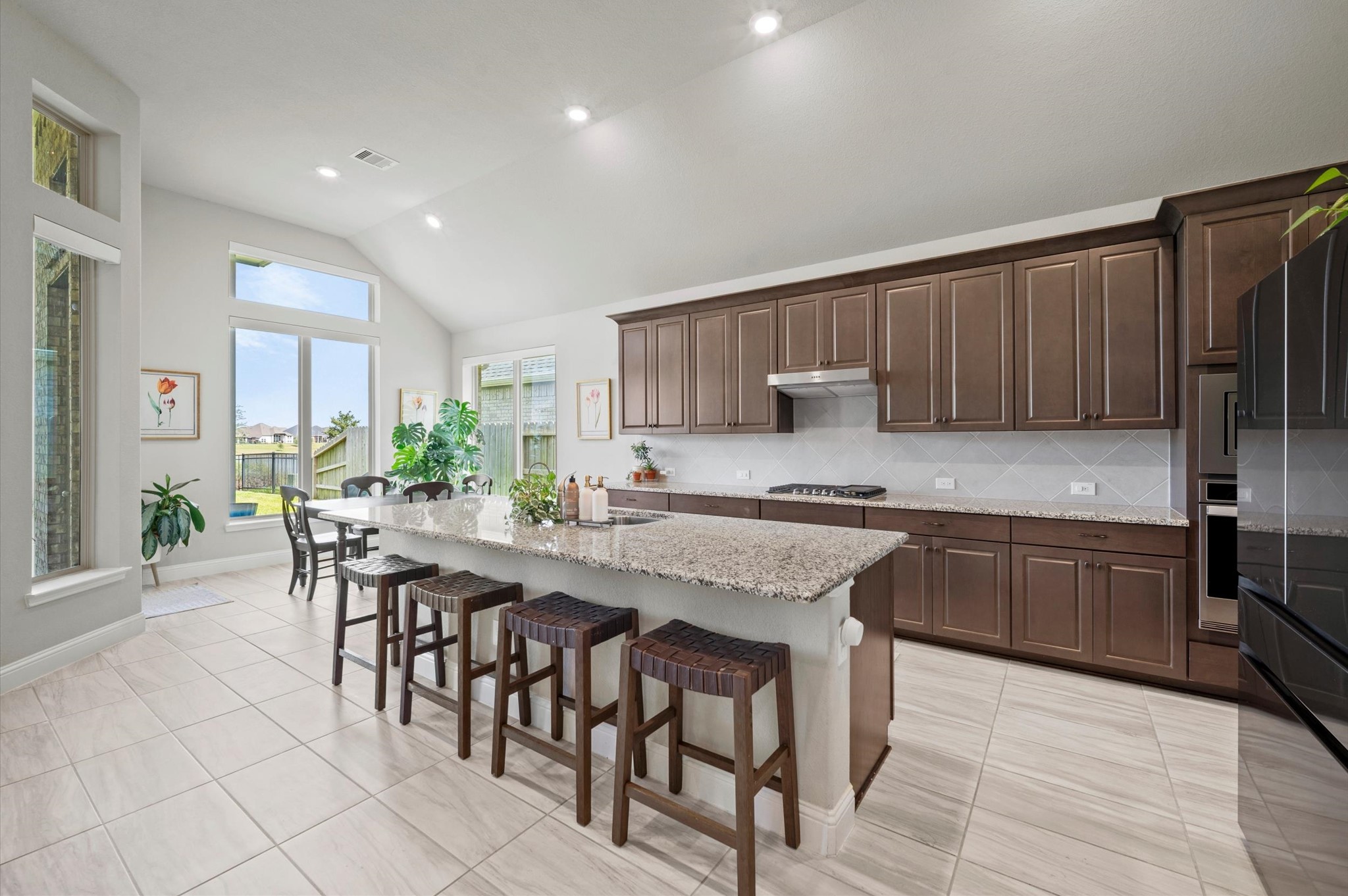 Spacious and bright kitchen featuring sleek dark wood cabinetry, a large granite island with seating, and plenty of natural light.