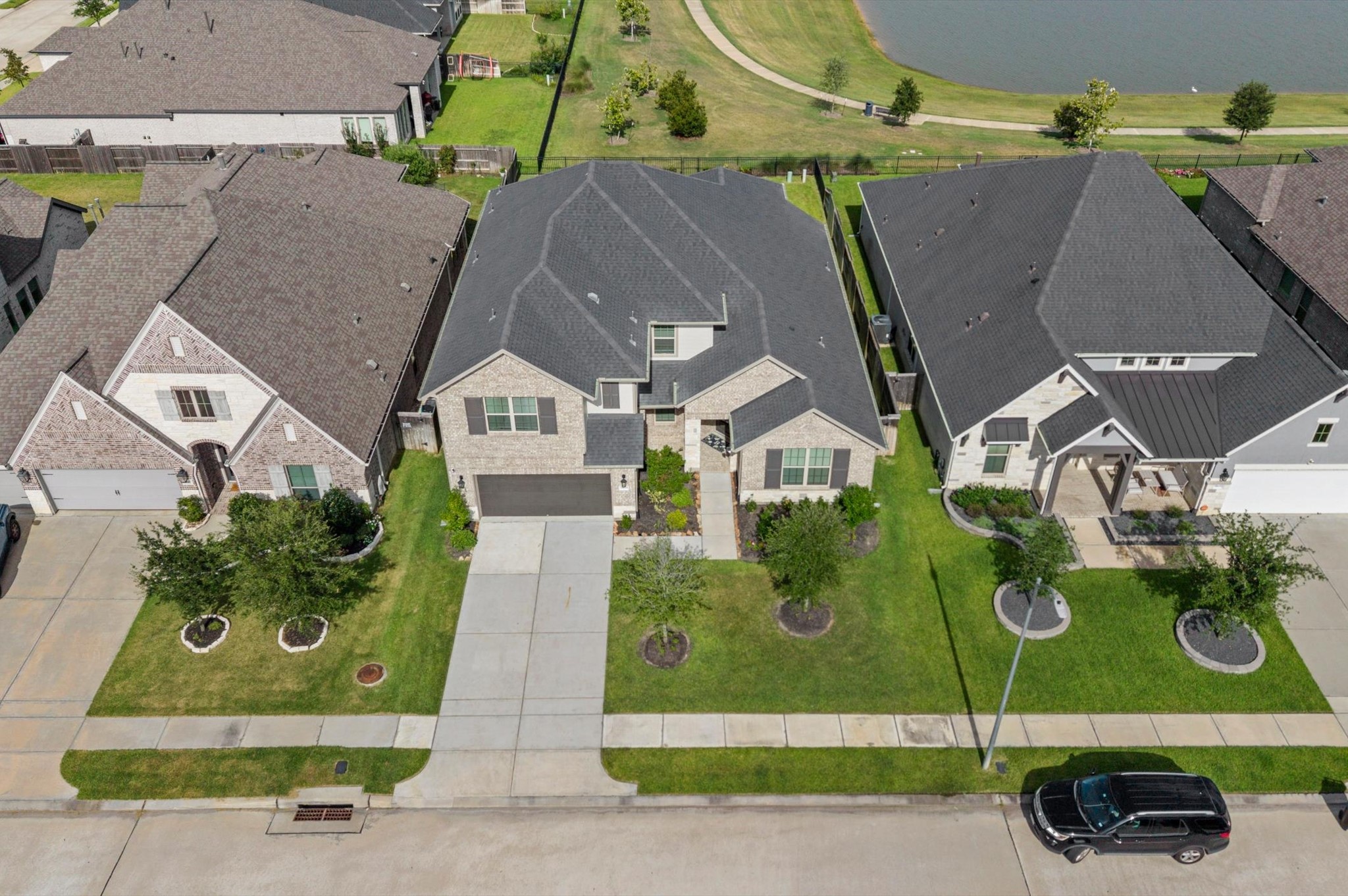 Charming two-story home with a spacious driveway, elegant brick facade, and manicured front lawn. Located in a serene neighborhood with a picturesque view of the lake.
