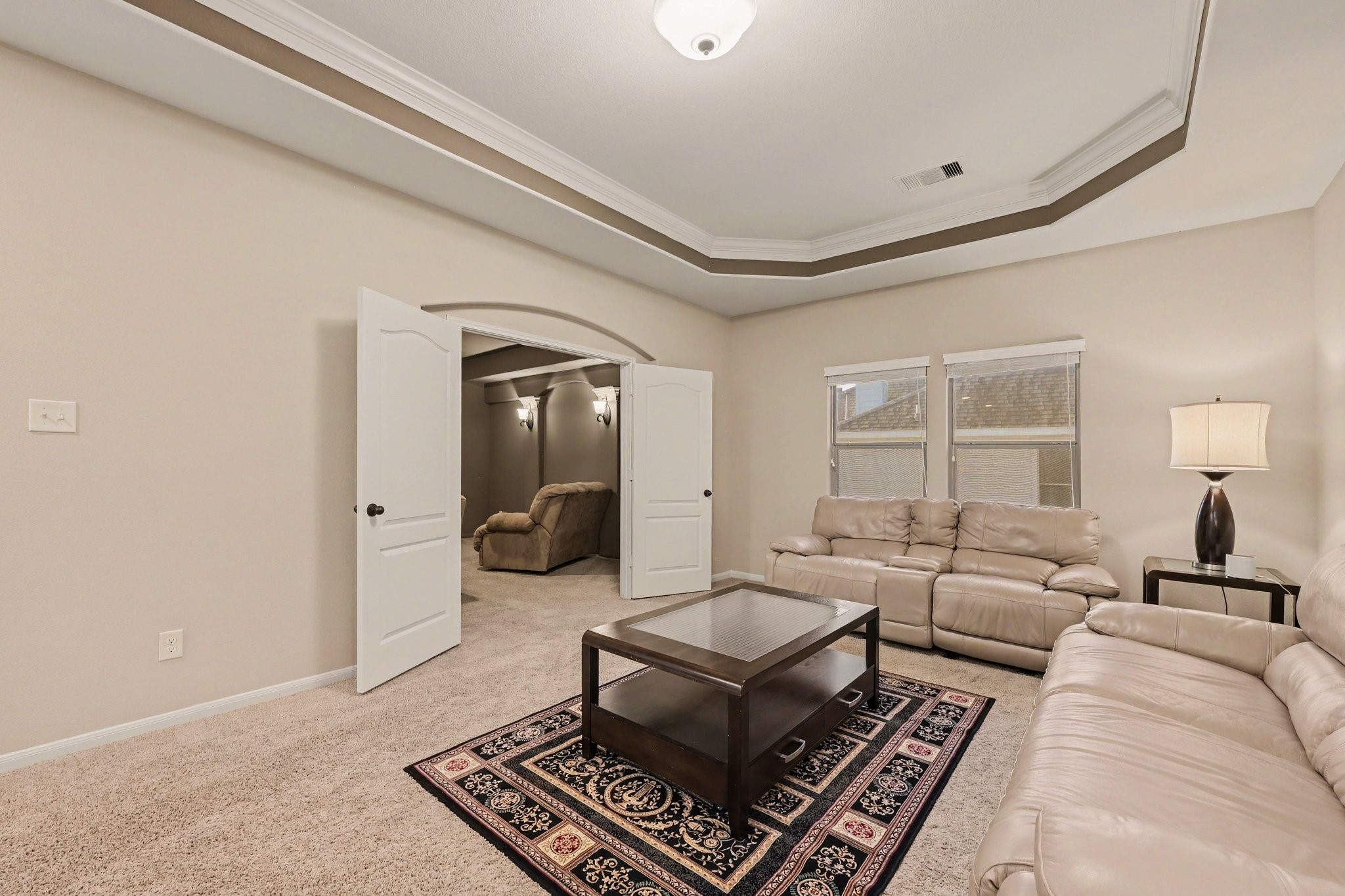 Another view of the upstairs den, featuring a tray ceiling with crown molding and convenient access to the adjacent media room.