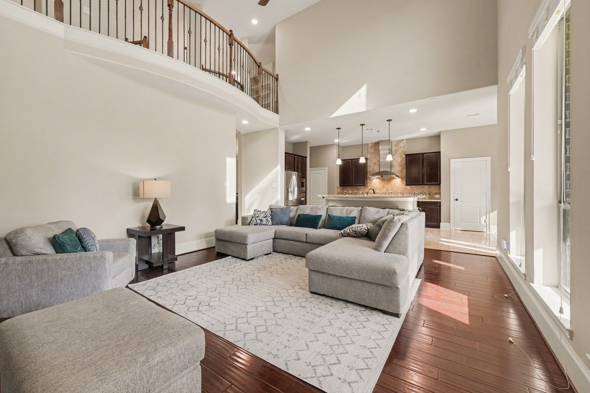 Impressive two-story living room with soaring ceilings, beautiful wood flooring, a fireplace, and an open layout