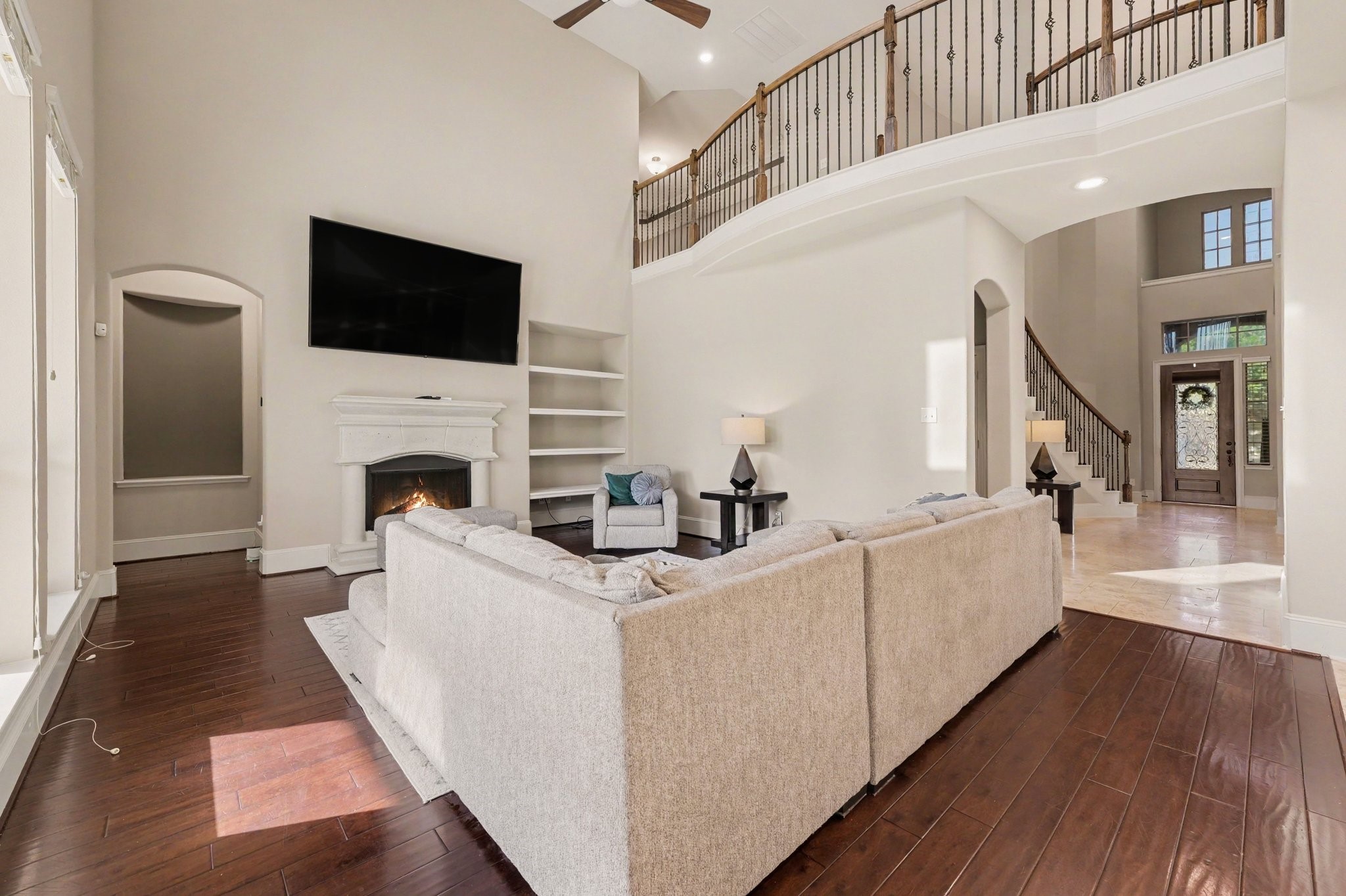 Impressive two-story living room with soaring ceilings, beautiful wood flooring, a fireplace, and an open layout