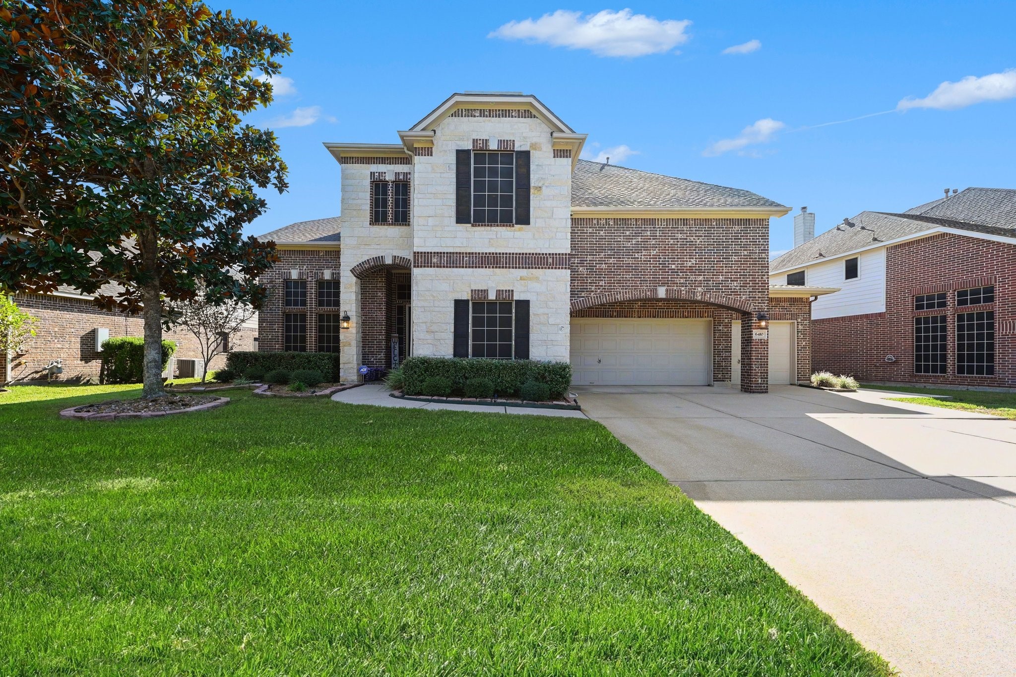 Impressive two-story home with beautiful brick and stone accents, a three-car garage, and an expansive driveway.