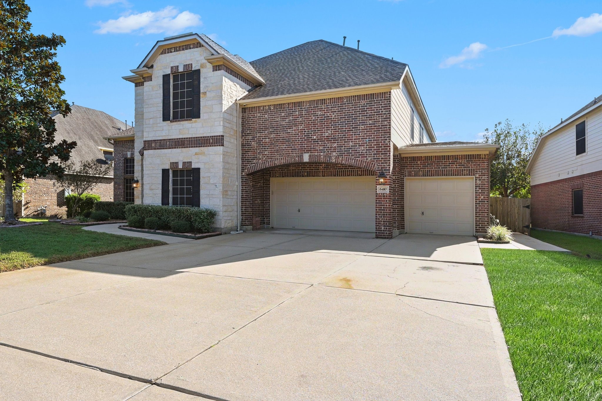Impressive two-story home with beautiful brick and stone accents, a three-car garage, and an expansive driveway.