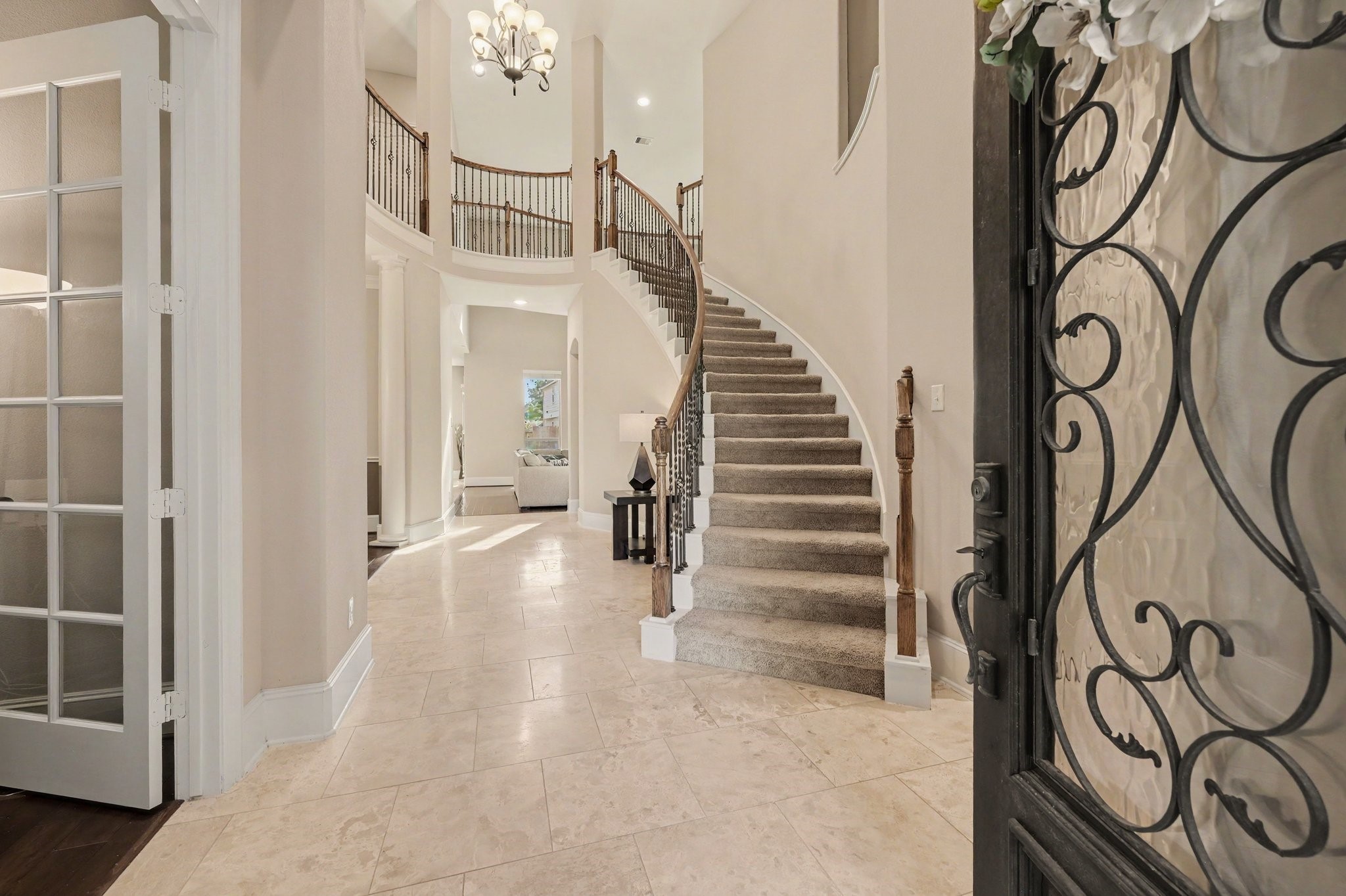 Grand two-story entry featuring a sweeping curved staircase, elegant wrought-iron railings, and soaring ceilings.