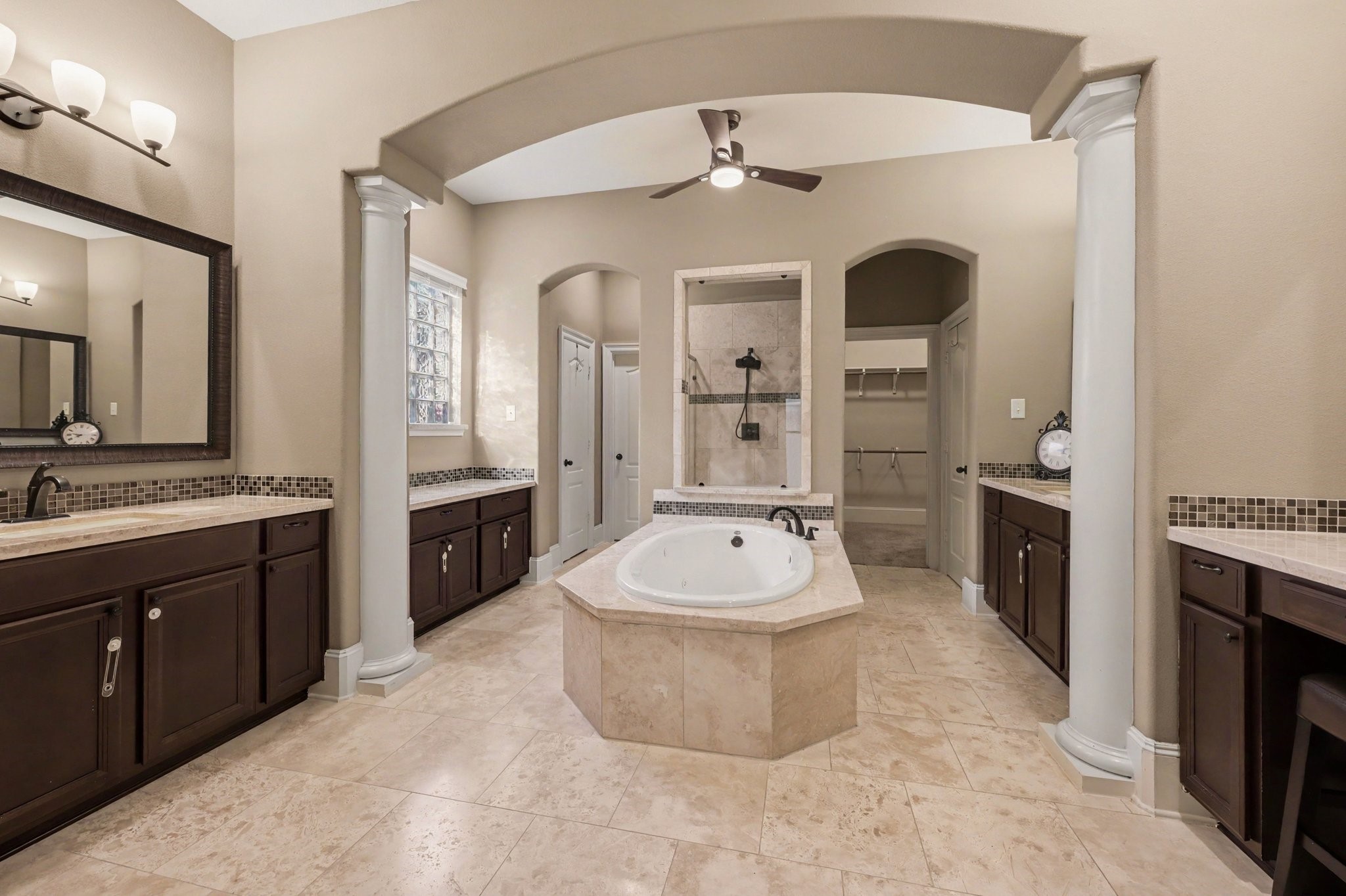 Spacious primary bathroom featuring a jetted soaking tub, separate walk-in shower, dual vanities, and two walk-in closets.