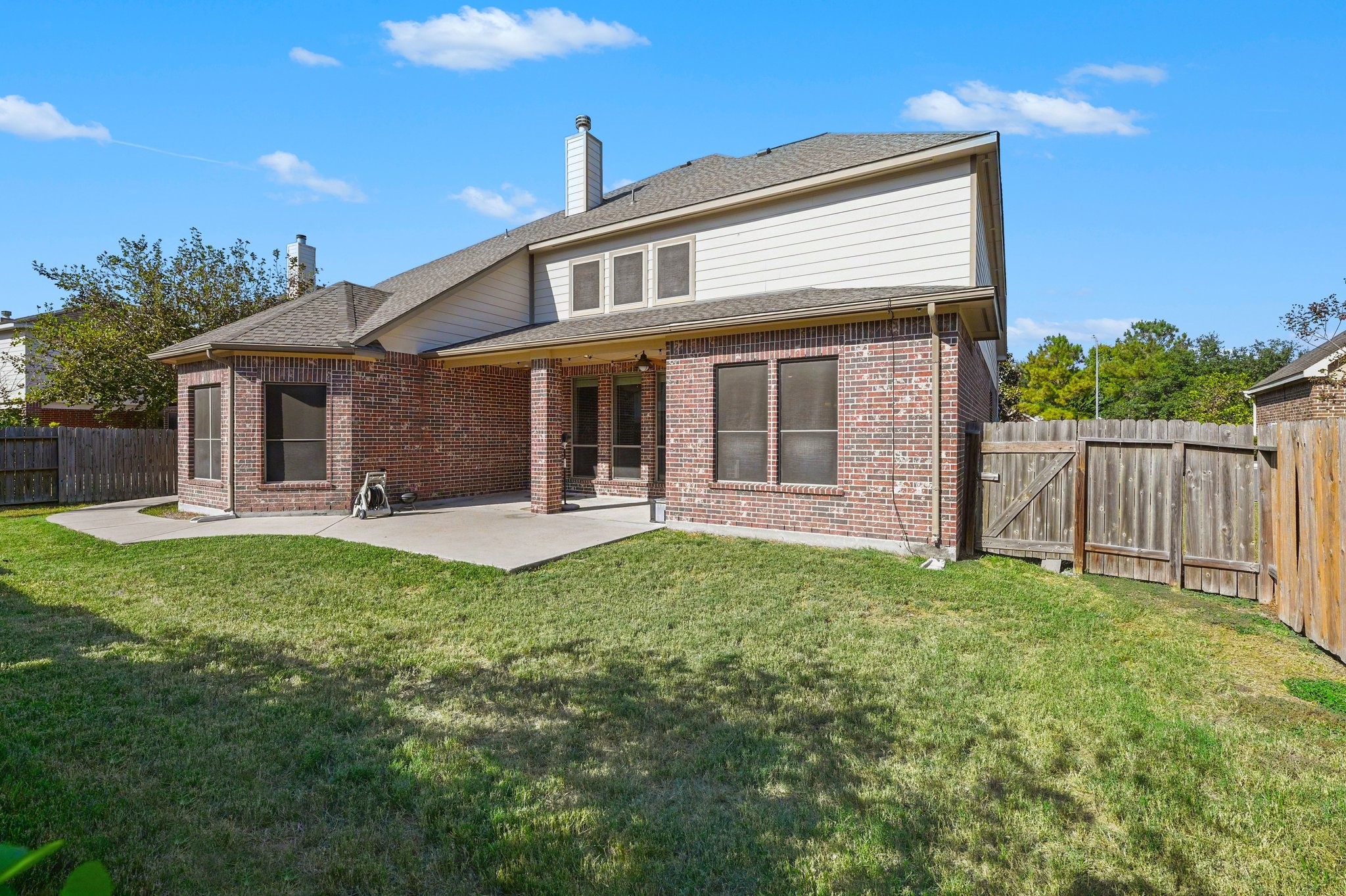 The backyard with a large covered patio, perfect for outdoor dining, entertaining, or relaxing.